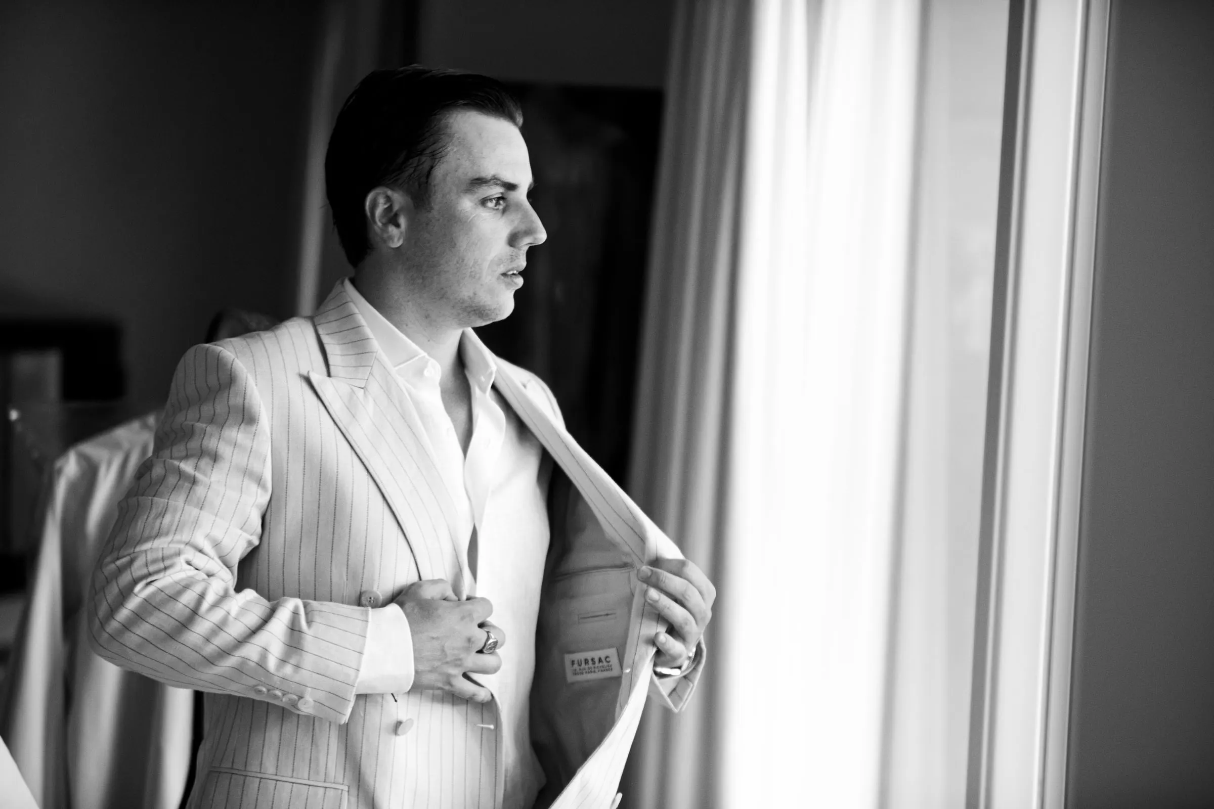 El novio se pone la americana de rayas junto a la ventana, en blanco y negro, Barbillón, Marbella