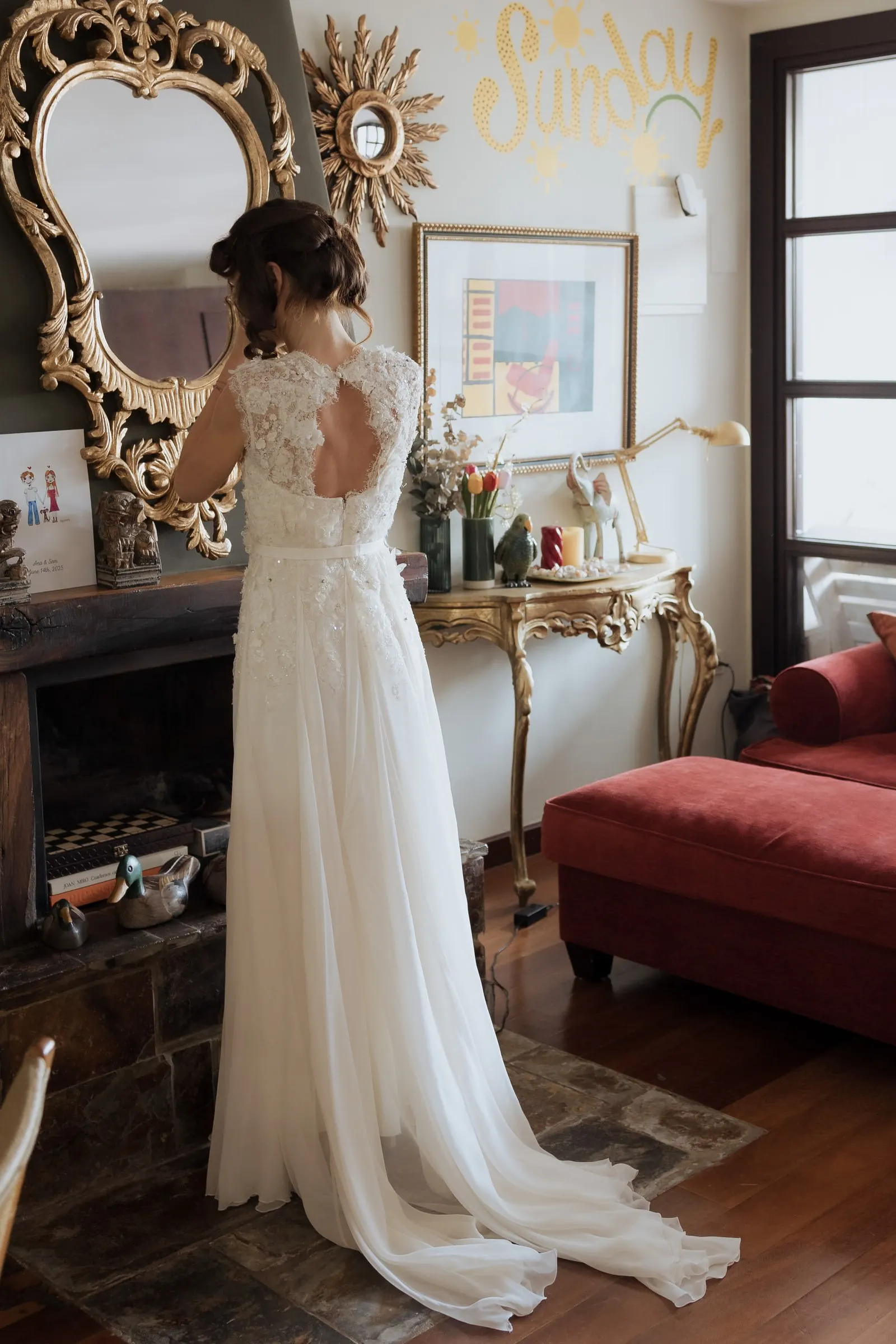 Bride in her lace-back gown before a gilded mirror in a room with a red sofa, Barbillón, Marbella