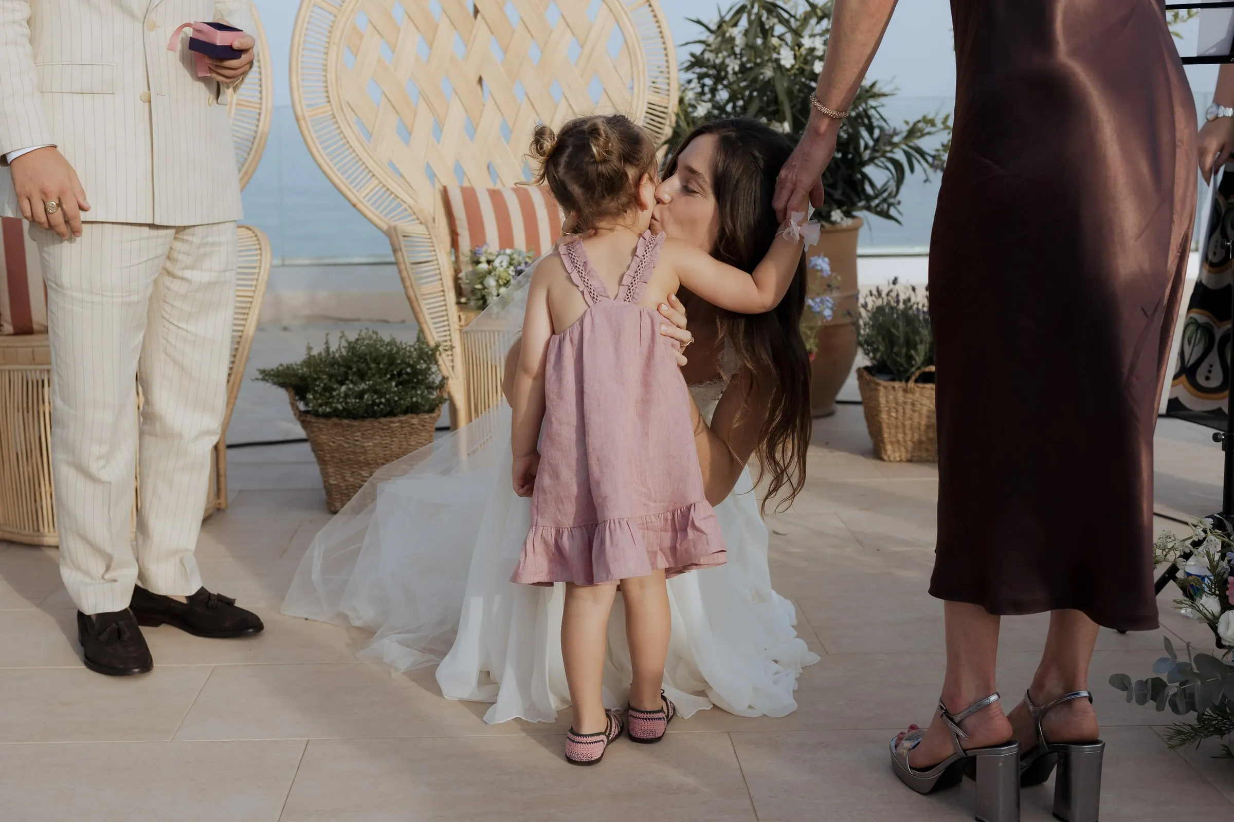 Little girl in a pink dress hugging the kneeling bride during the ceremony at Barbillón, Marbella