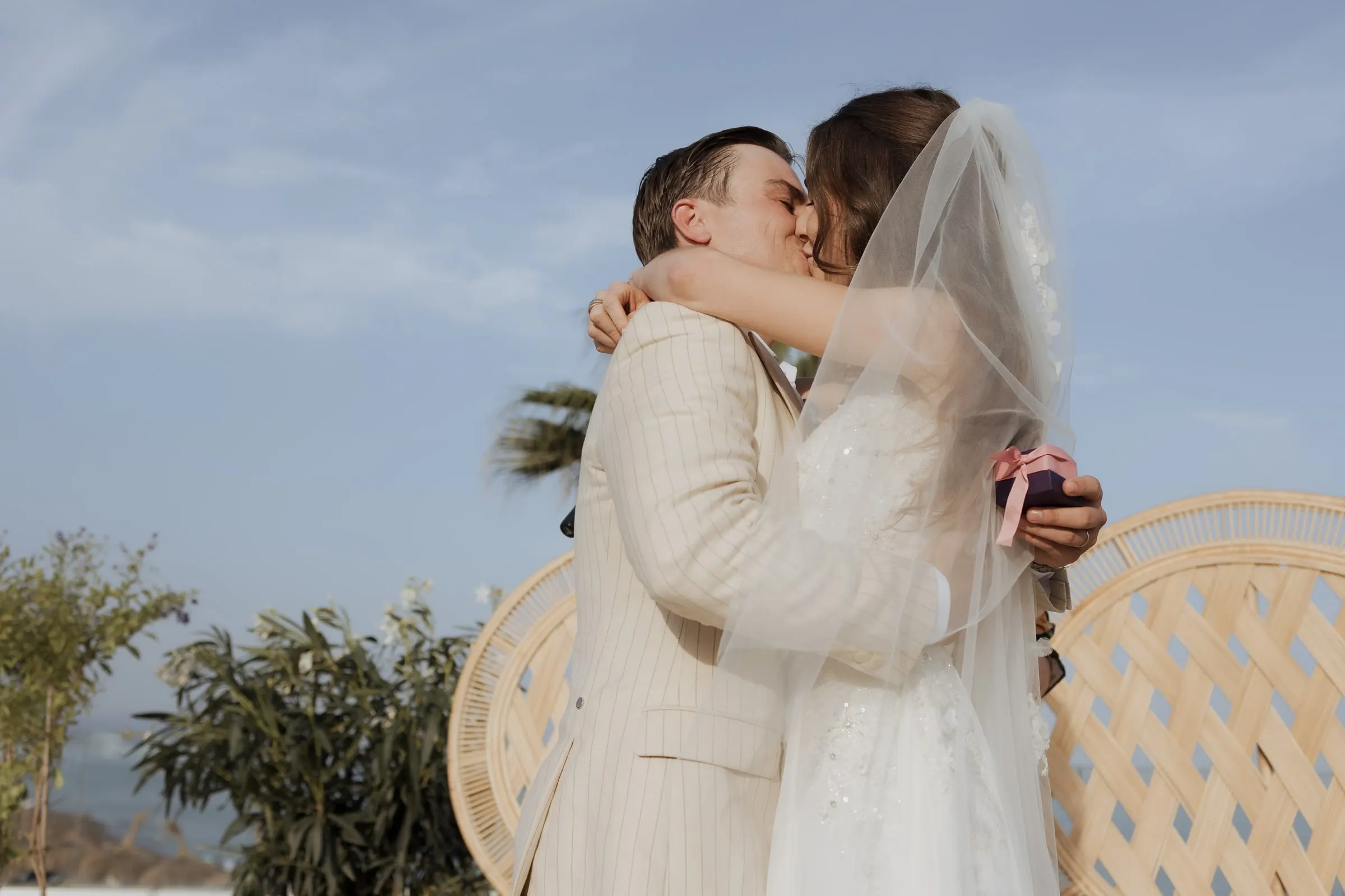 Bride and groom kissing in front of the wicker peacock chairs at their ceremony at Barbillón, Marbella