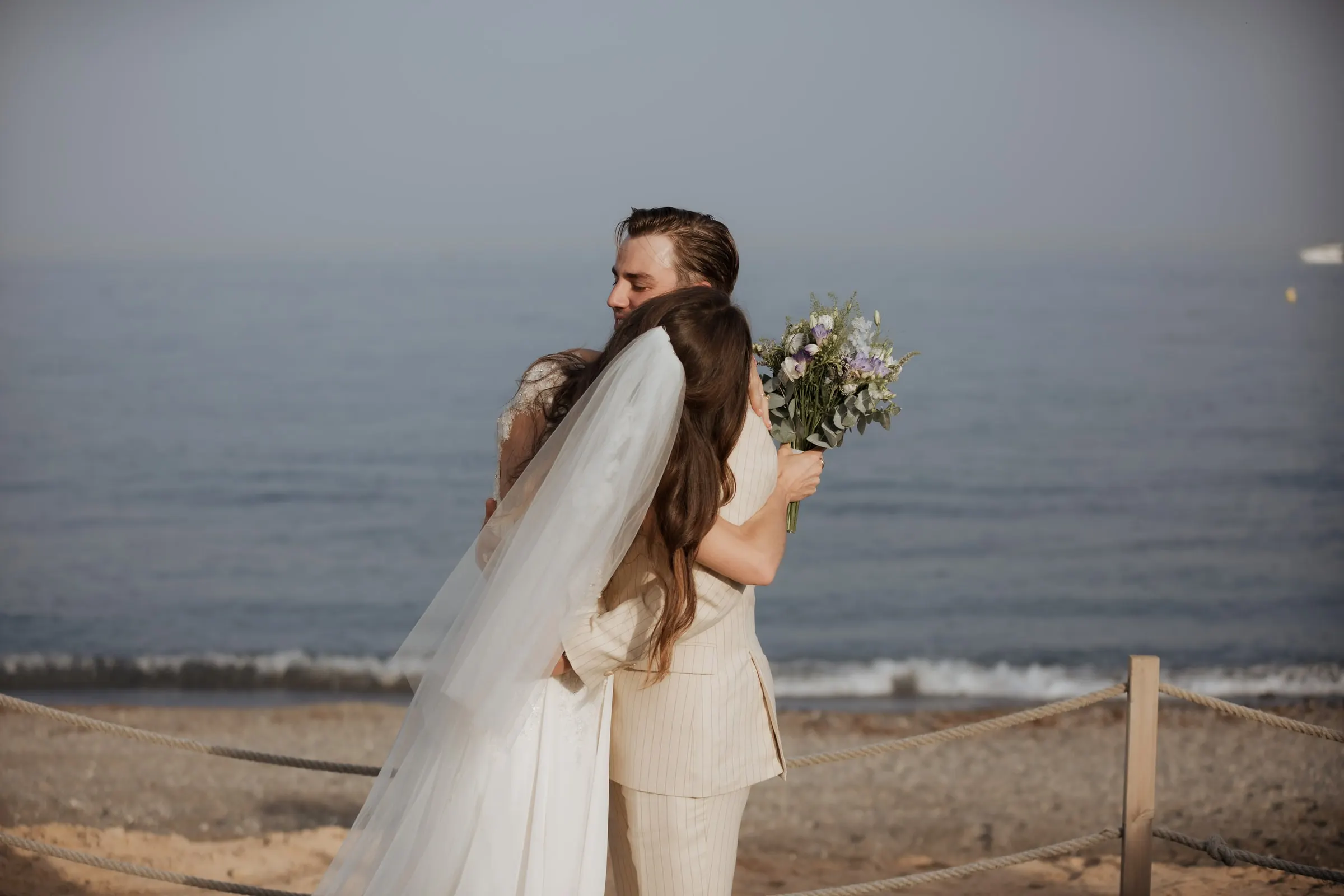 Bride and groom hugging on the beach by the sea at Barbillón, Marbella