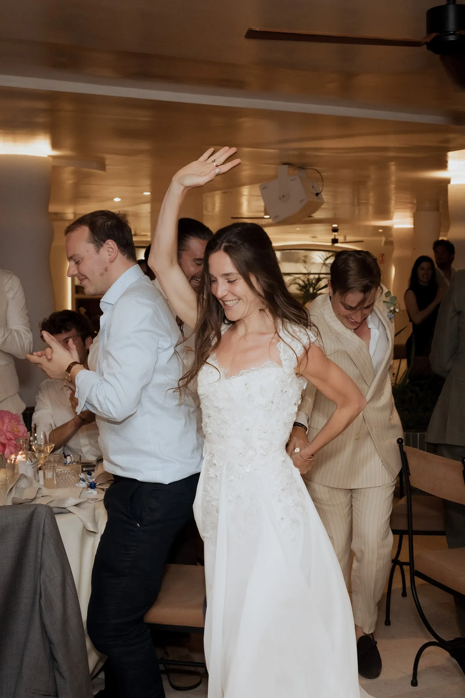 Bride dancing with one arm raised among guests in the restaurant at Barbillón, Marbella