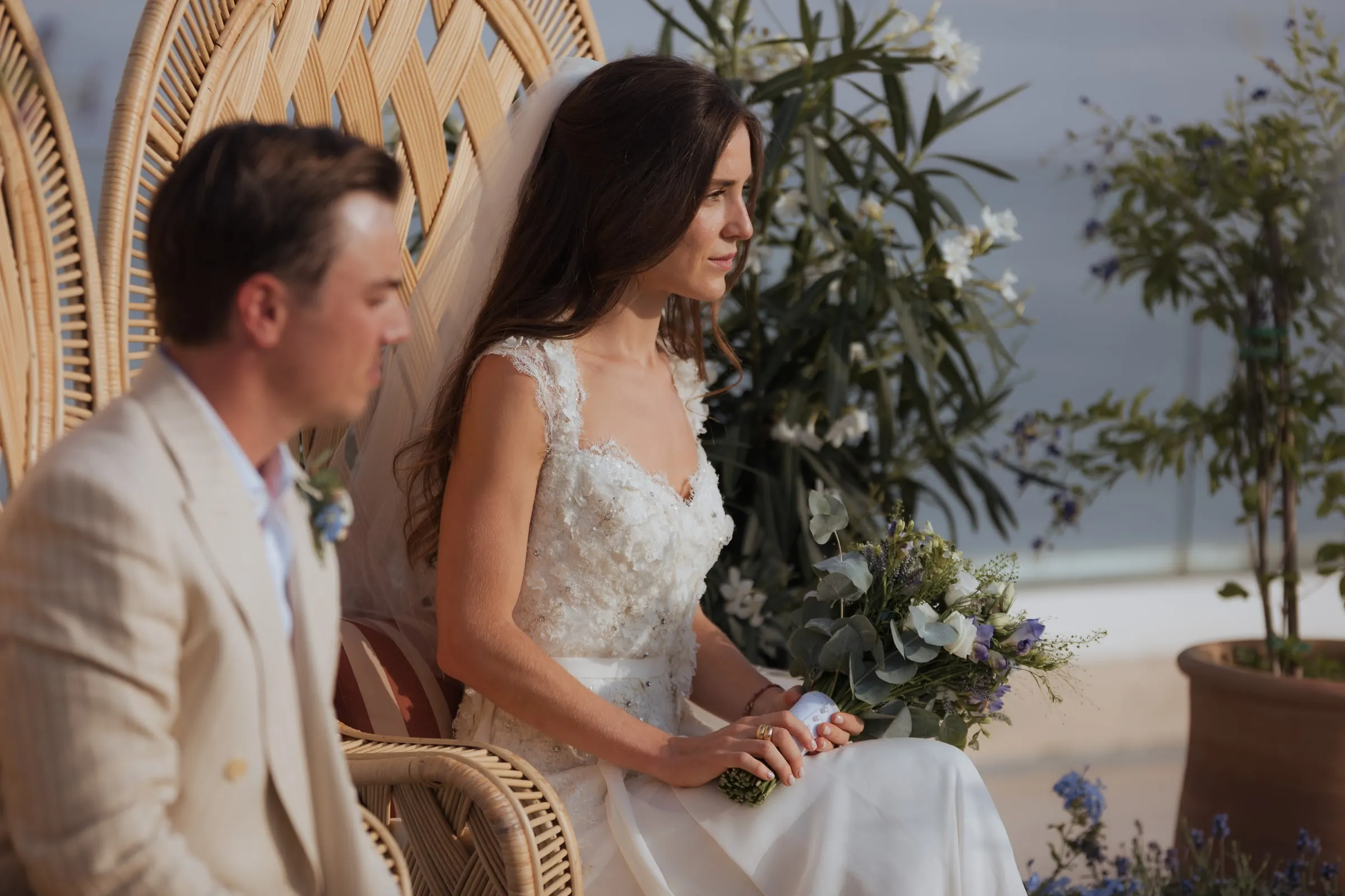Bride and groom seated side by side in wicker chairs during the ceremony, Barbillón, Marbella