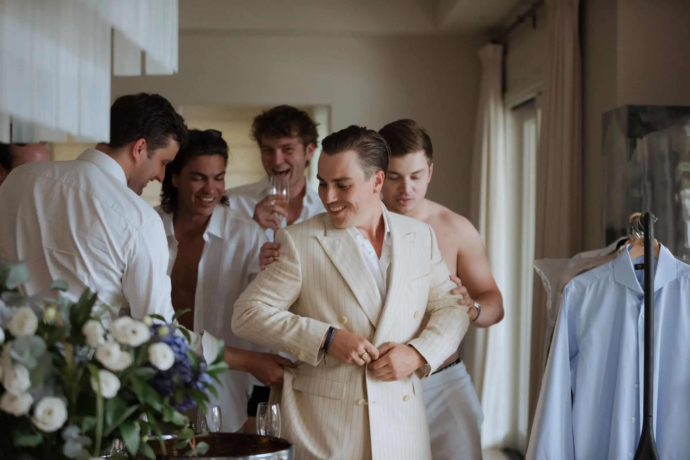 Friend helping the groom into his cream jacket as the others watch, Barbillón, Marbella