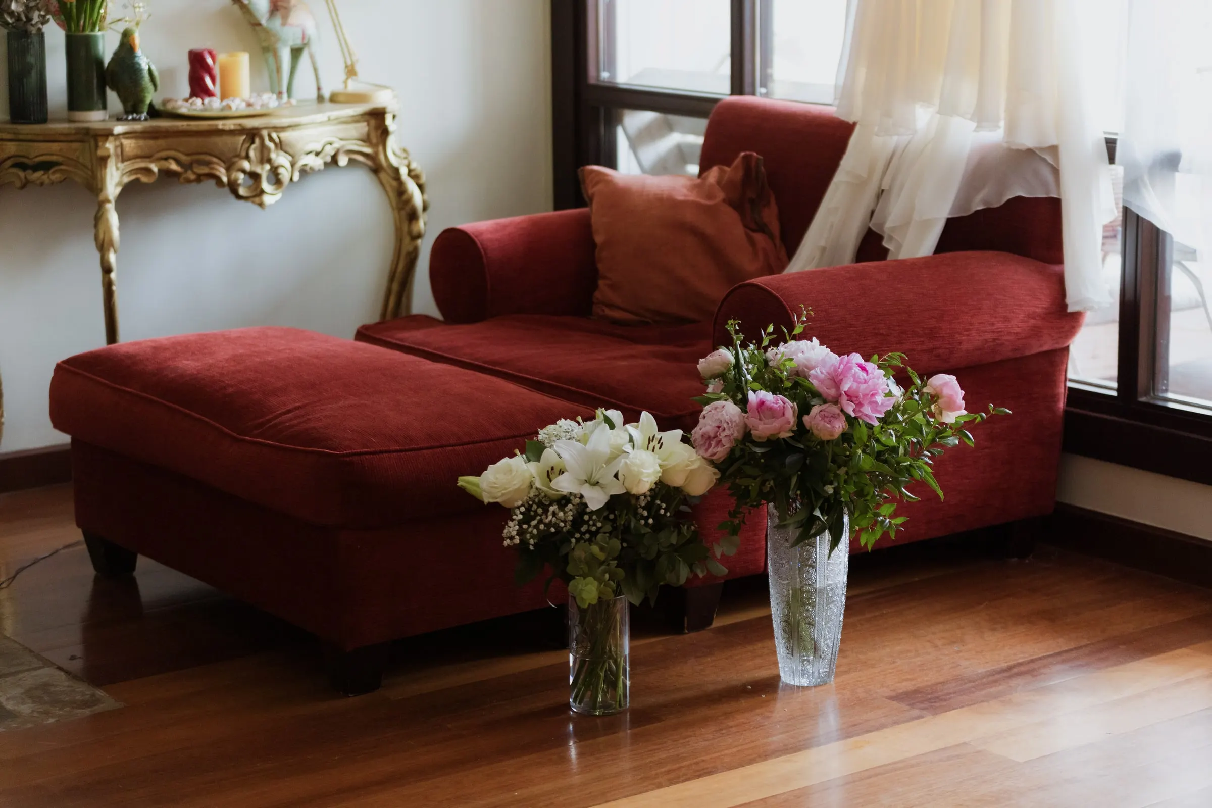 Two vases of peonies and lilies on the floor beside a red chaise longue, Barbillón, Marbella