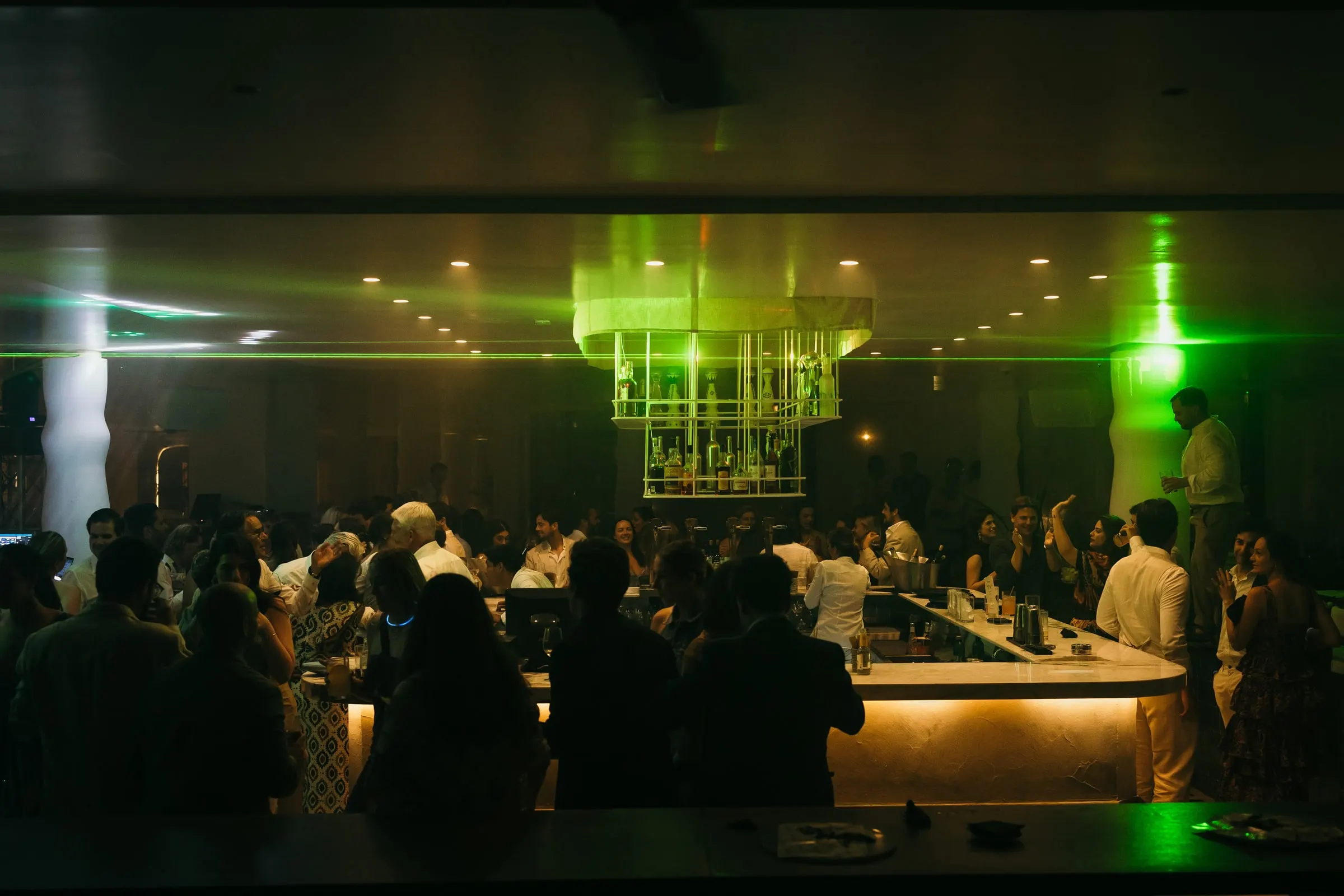 La barra llena de invitados bajo luces verdes durante la fiesta de la boda, Barbillón, Marbella