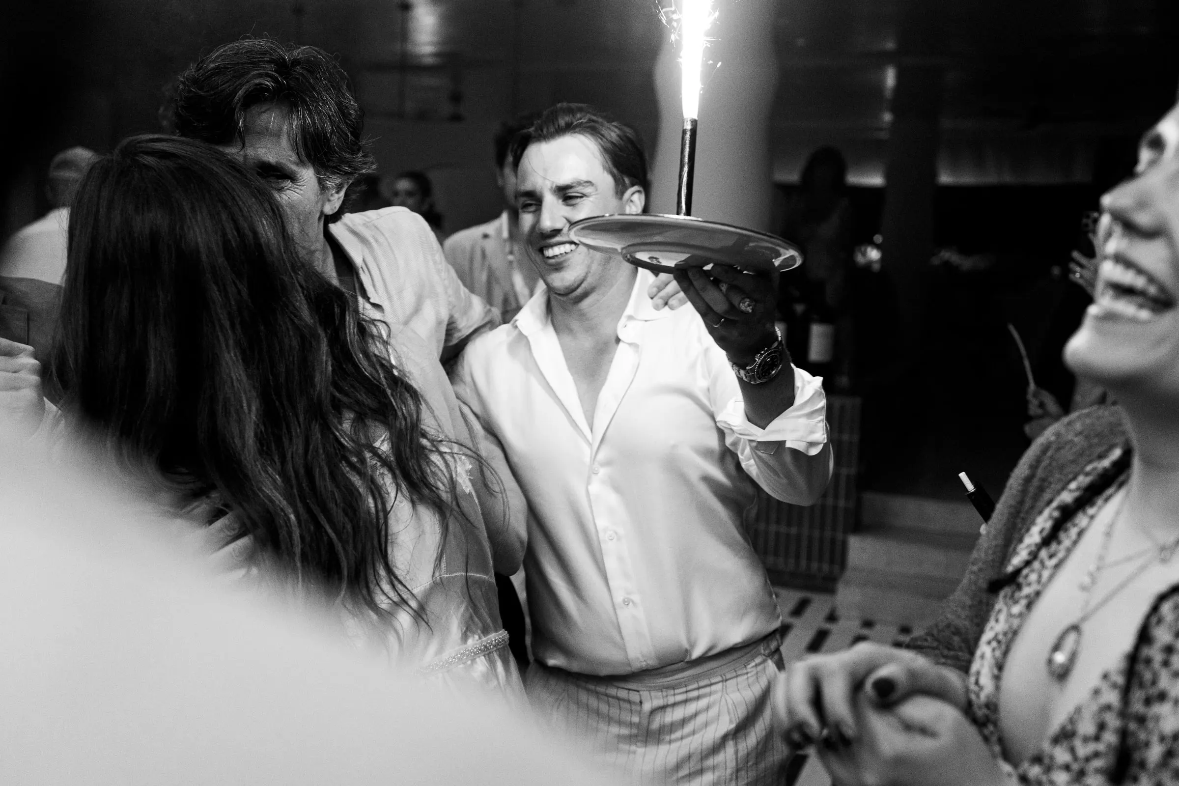 Black and white of the groom carrying a plate with a sparkler at the party, Barbillón, Marbella