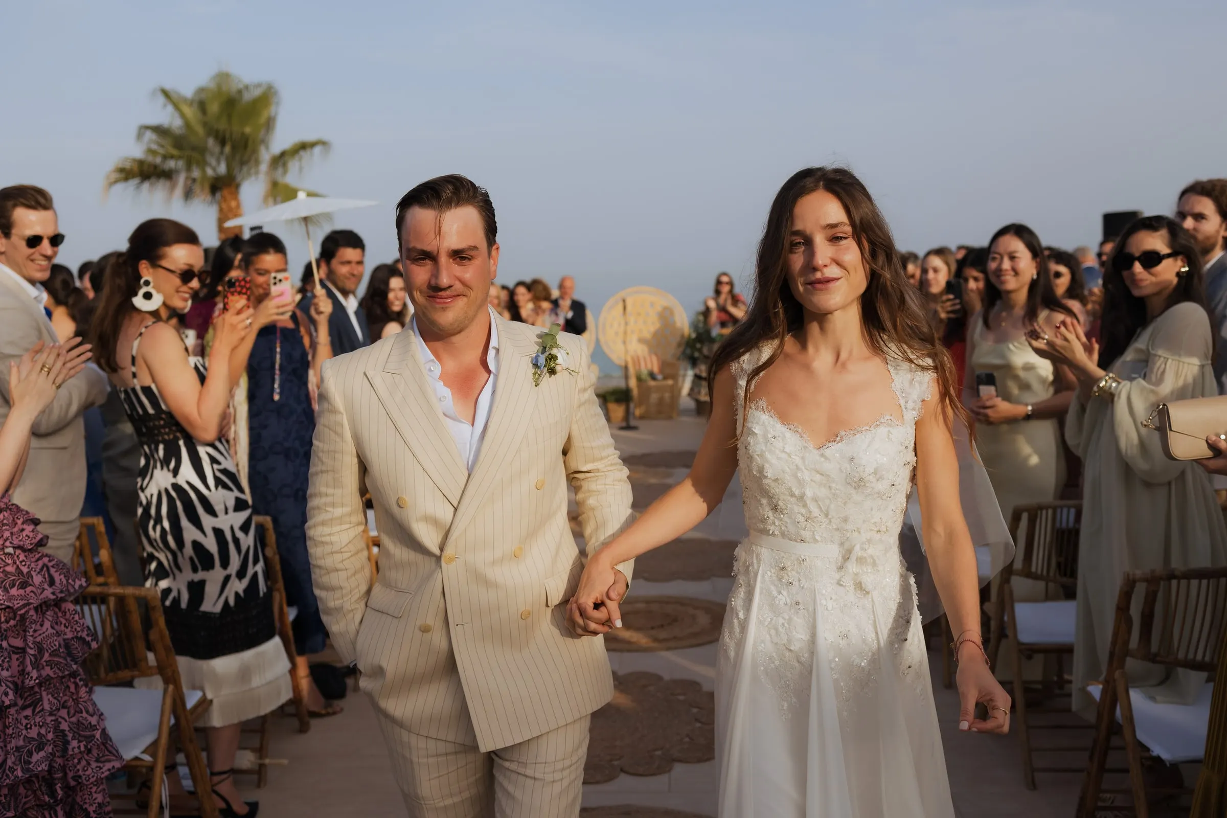 Bride and groom walking back up the aisle hand in hand as guests cheer, Barbillón, Marbella