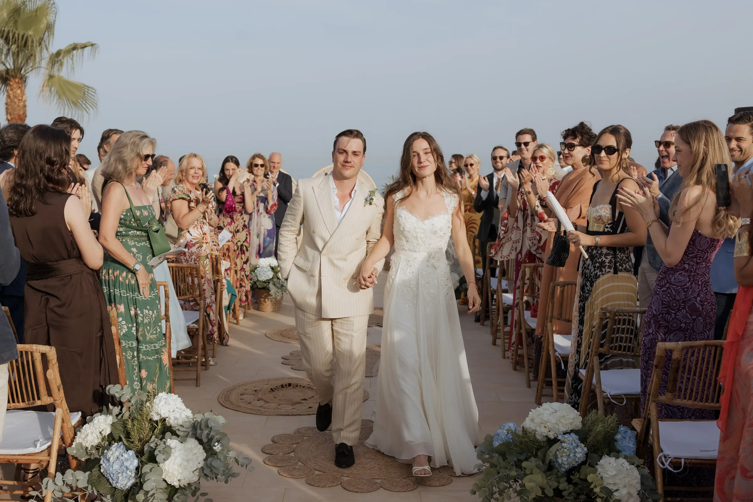 Newlyweds walking up the aisle among guests and blue hydrangeas, Barbillón, Marbella