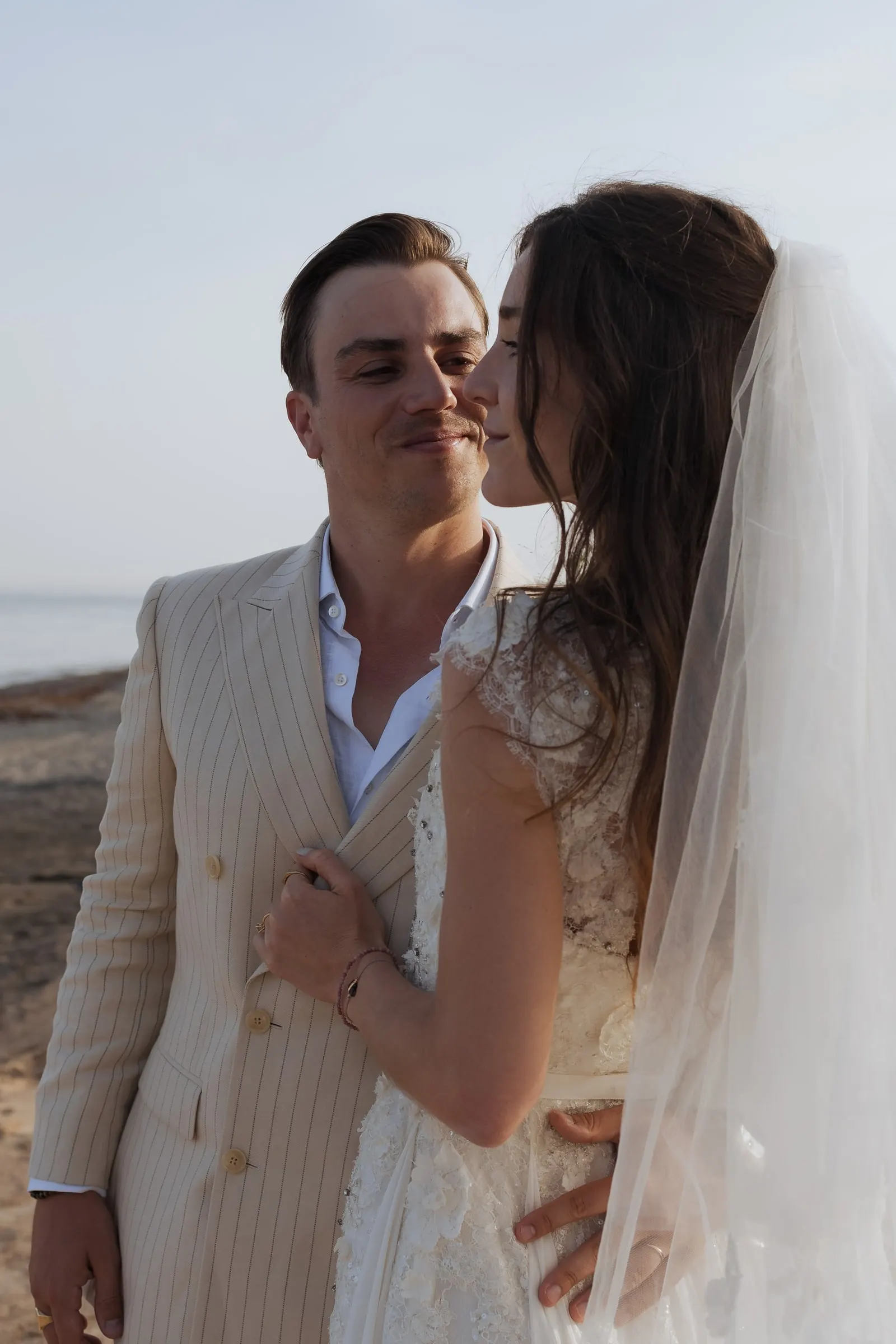 Bride kissing the groom's cheek in the evening light by the shore, Barbillón, Marbella