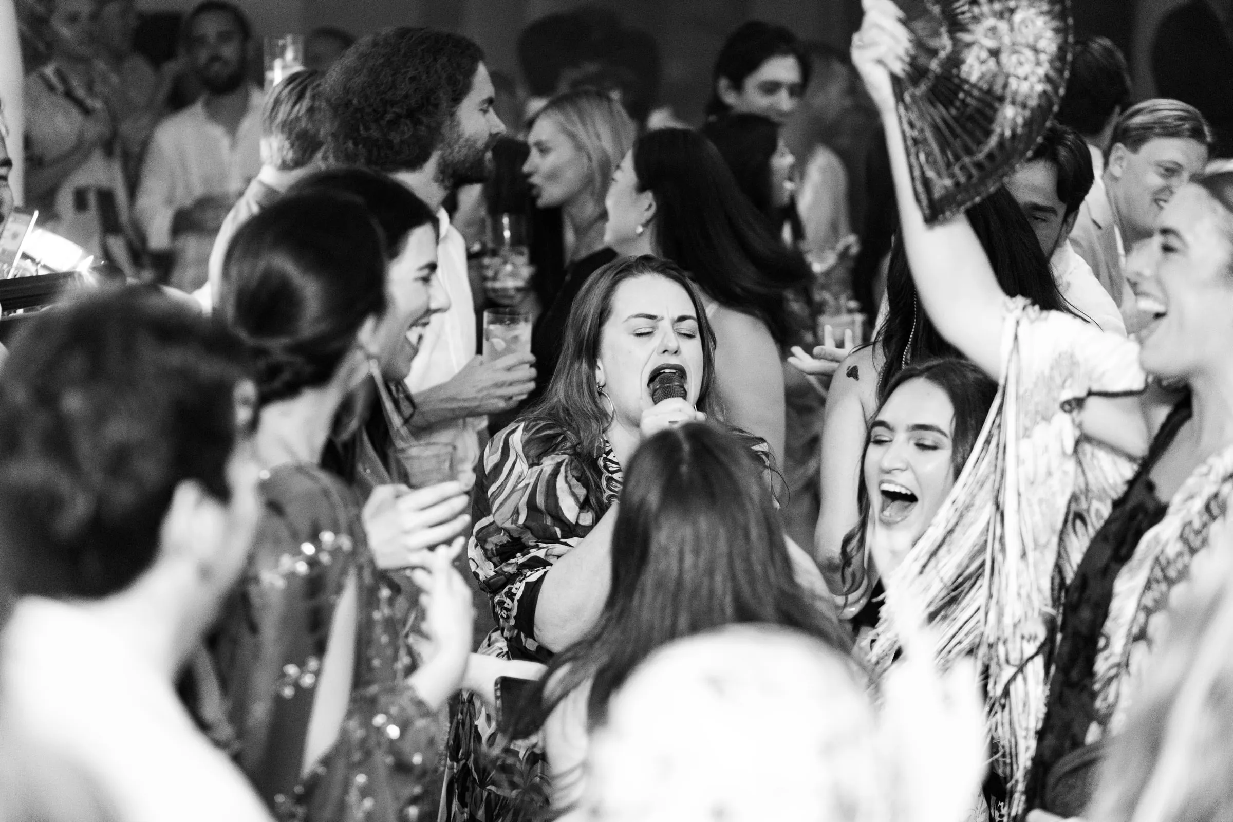 Black and white of a guest singing into a microphone on a packed dance floor, Barbillón, Marbella