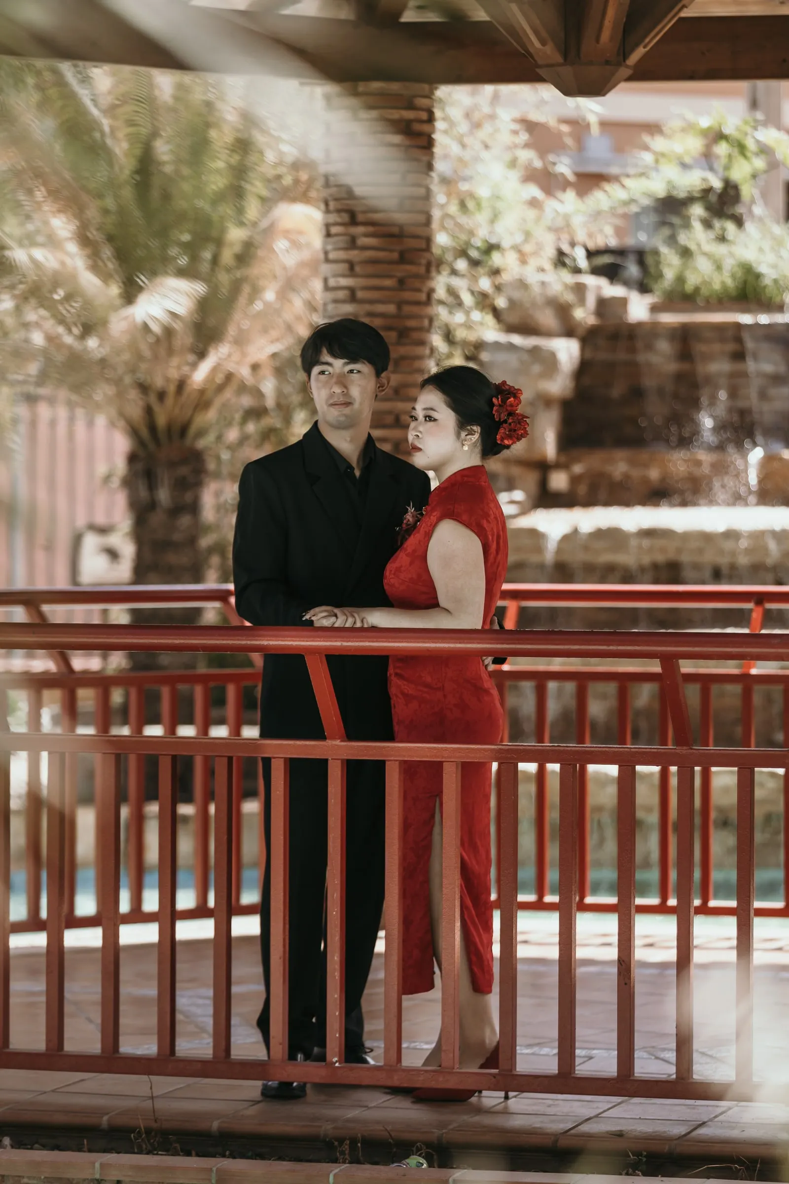 Couple in a red qipao and black suit by a red pavilion railing, Jardín Oriental Bienquerido, Alhaurín de la Torre
