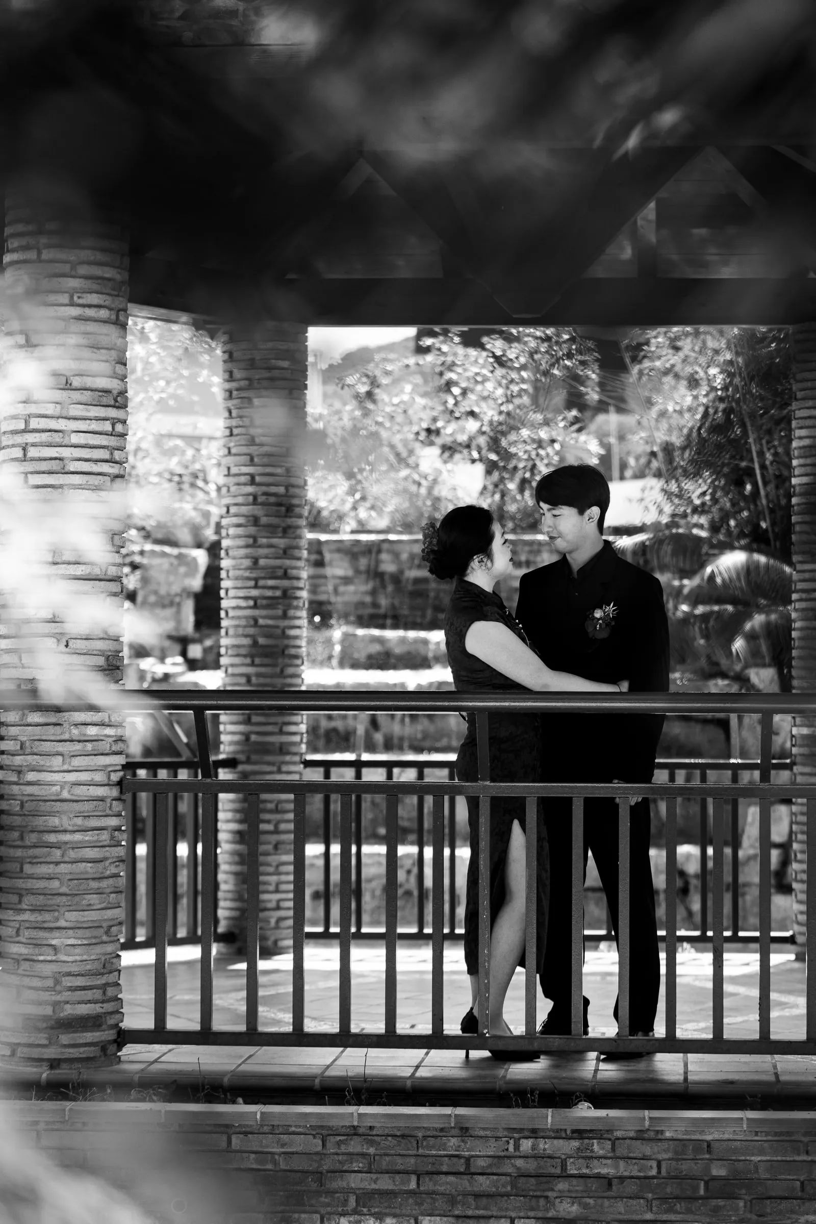 Black and white photo of the couple embracing under a brick pavilion in the Japanese garden of Alhaurín de la Torre