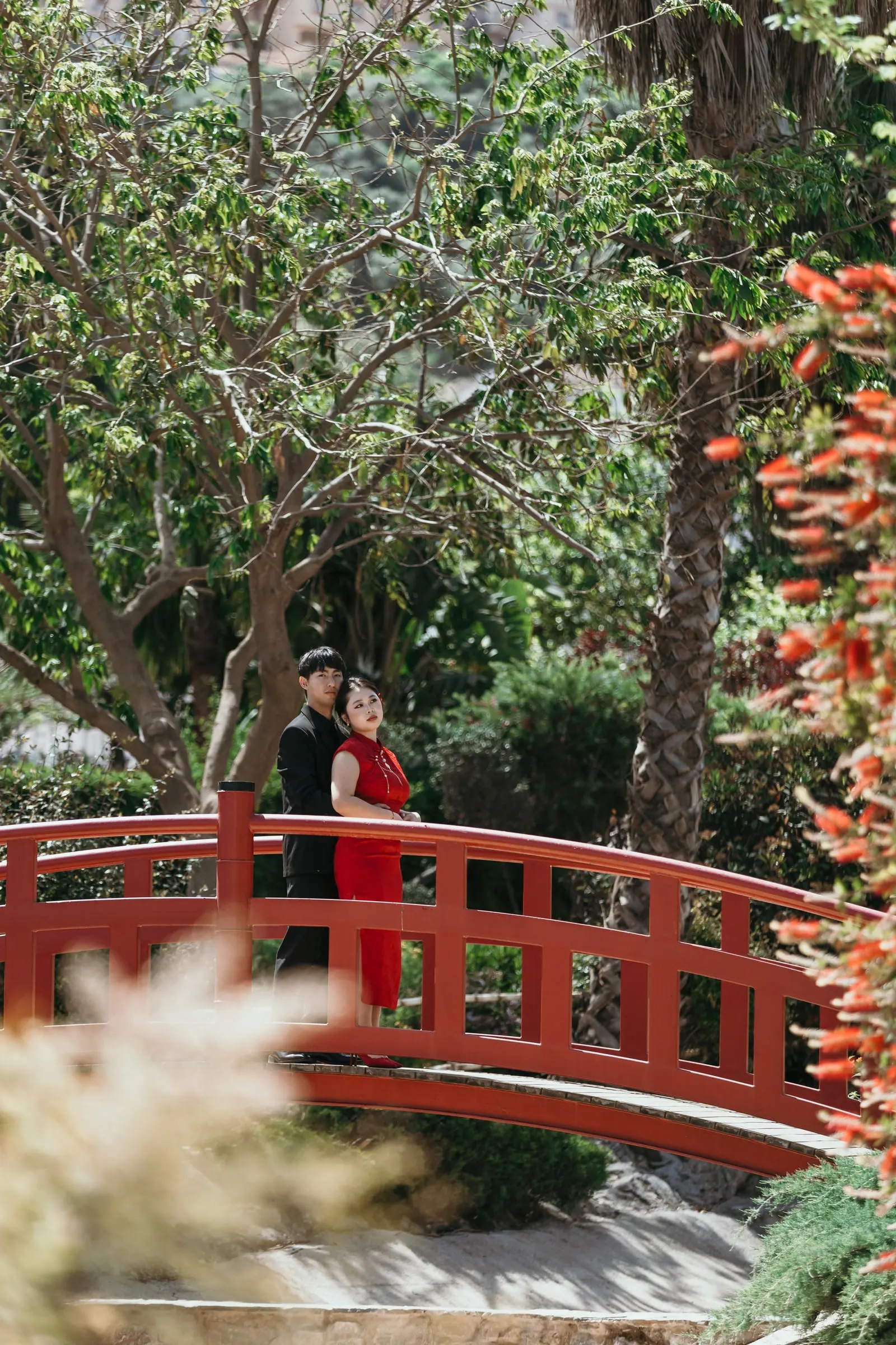 Couple on a red arched bridge among the trees of the Jardín Oriental Bienquerido