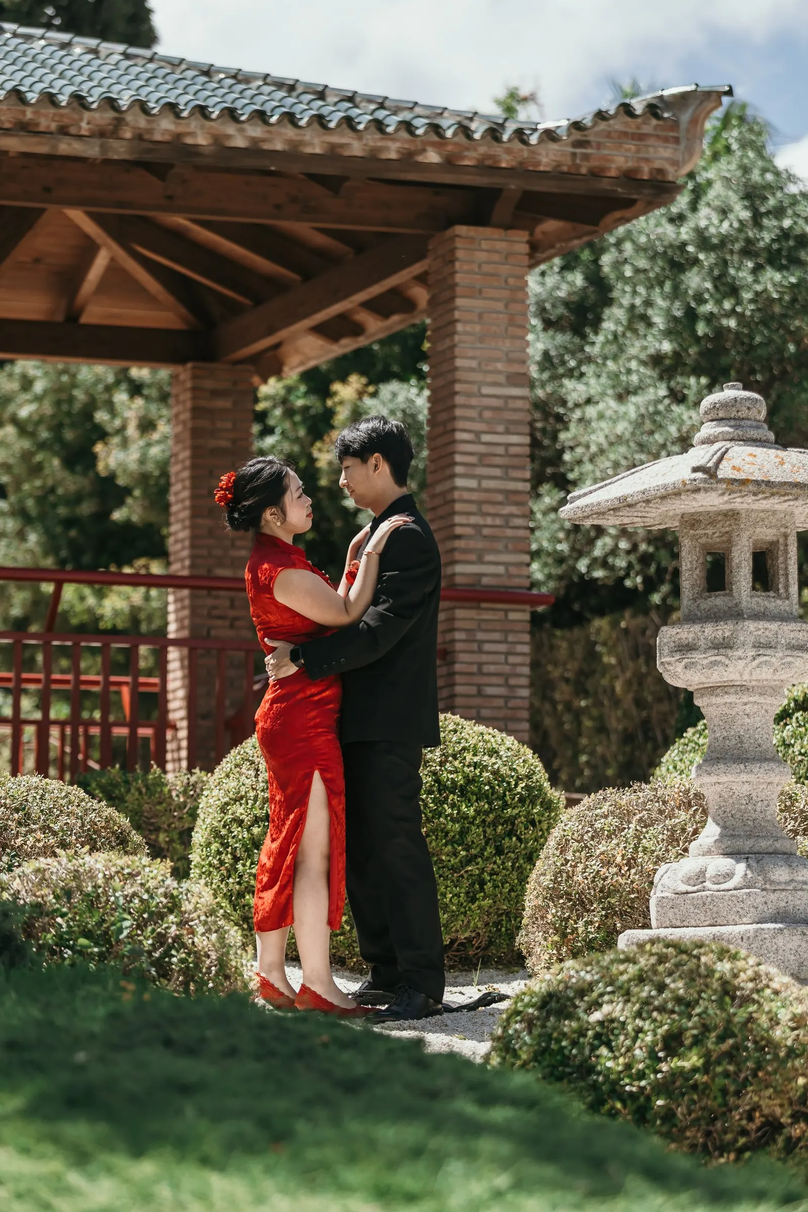Couple on the lawn between the pagoda, the stone lantern and the clipped shrubs of the Japanese garden