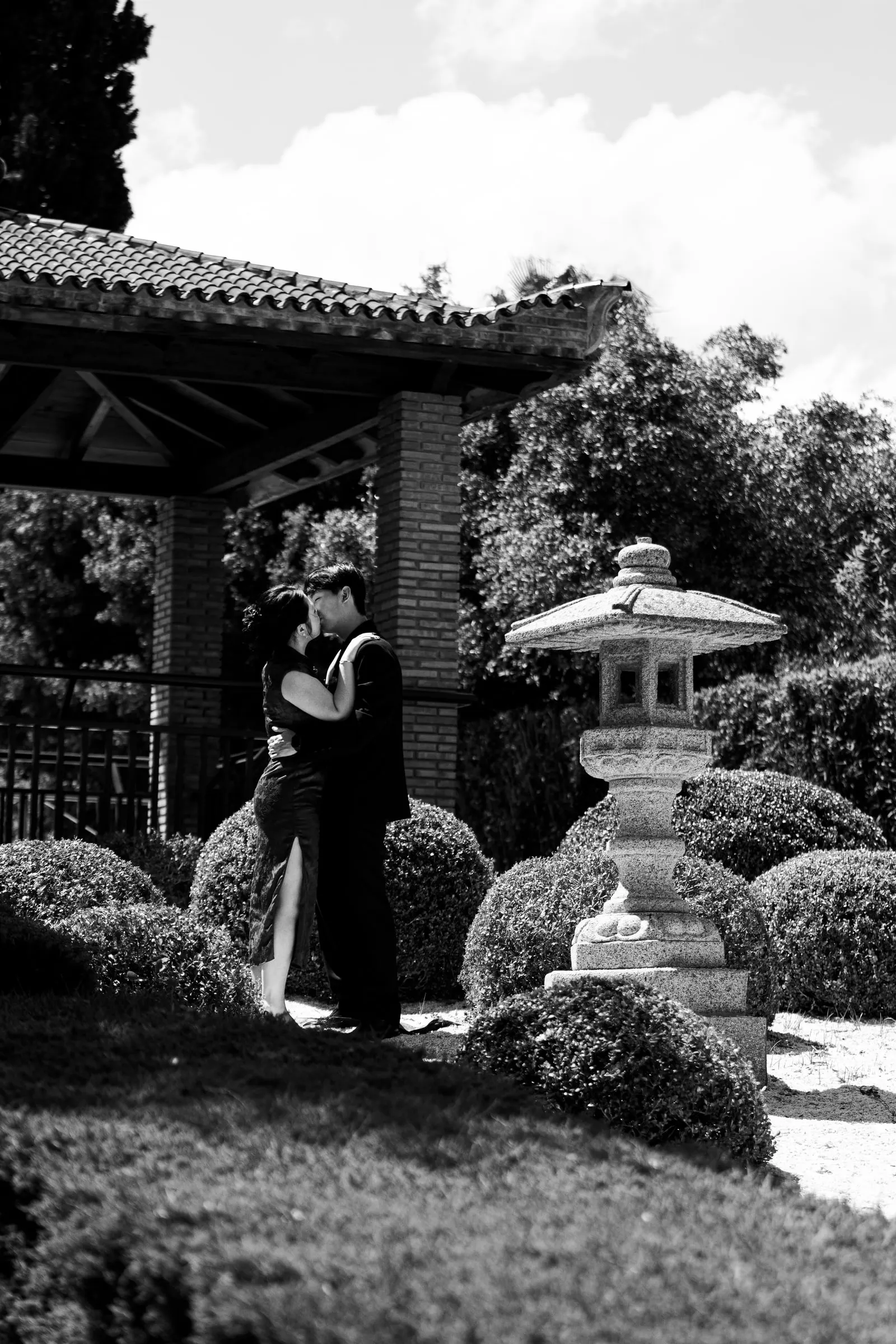 Black and white photo of the couple kissing beside the pagoda and the stone lantern