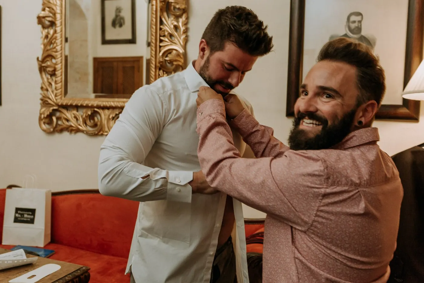 Friend in a pink shirt laughing as he helps the groom with his collar, Salamanca
