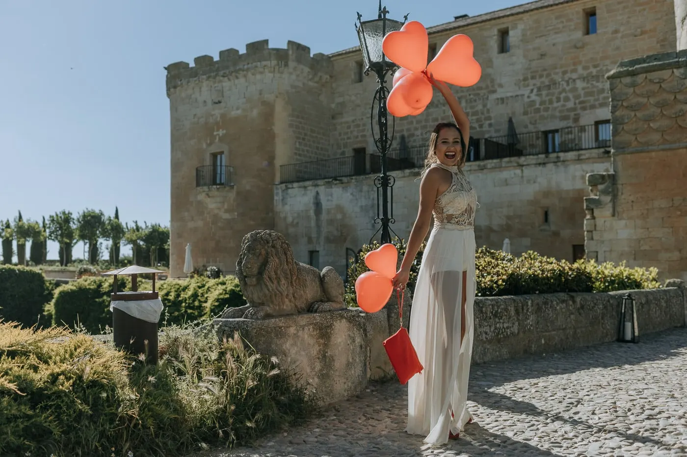 Guest with heart-shaped balloons in front of the battlements of Castillo del Buen Amor