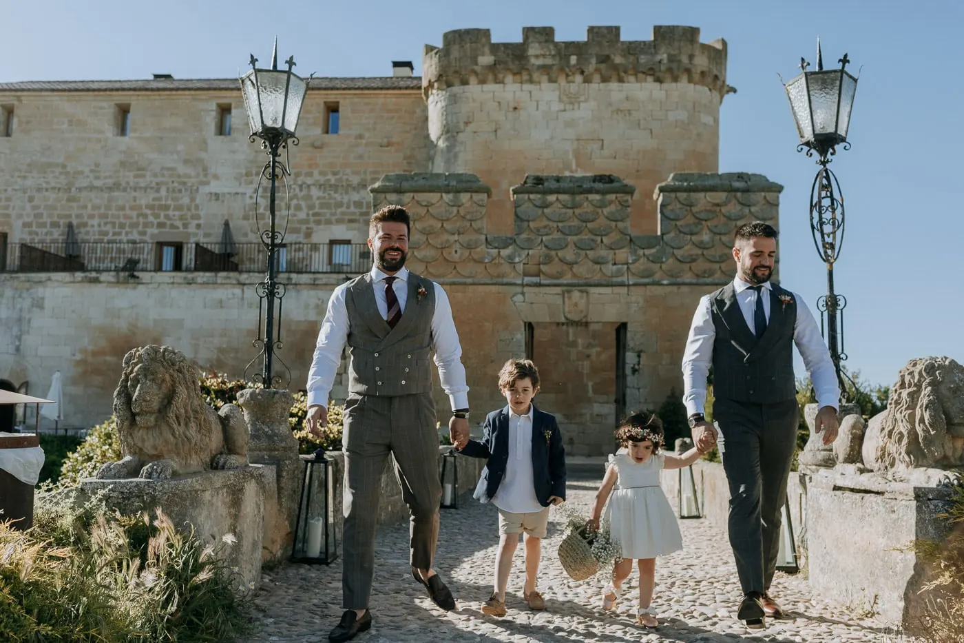 The grooms walking in with two children past the stone lions of the castle, Salamanca