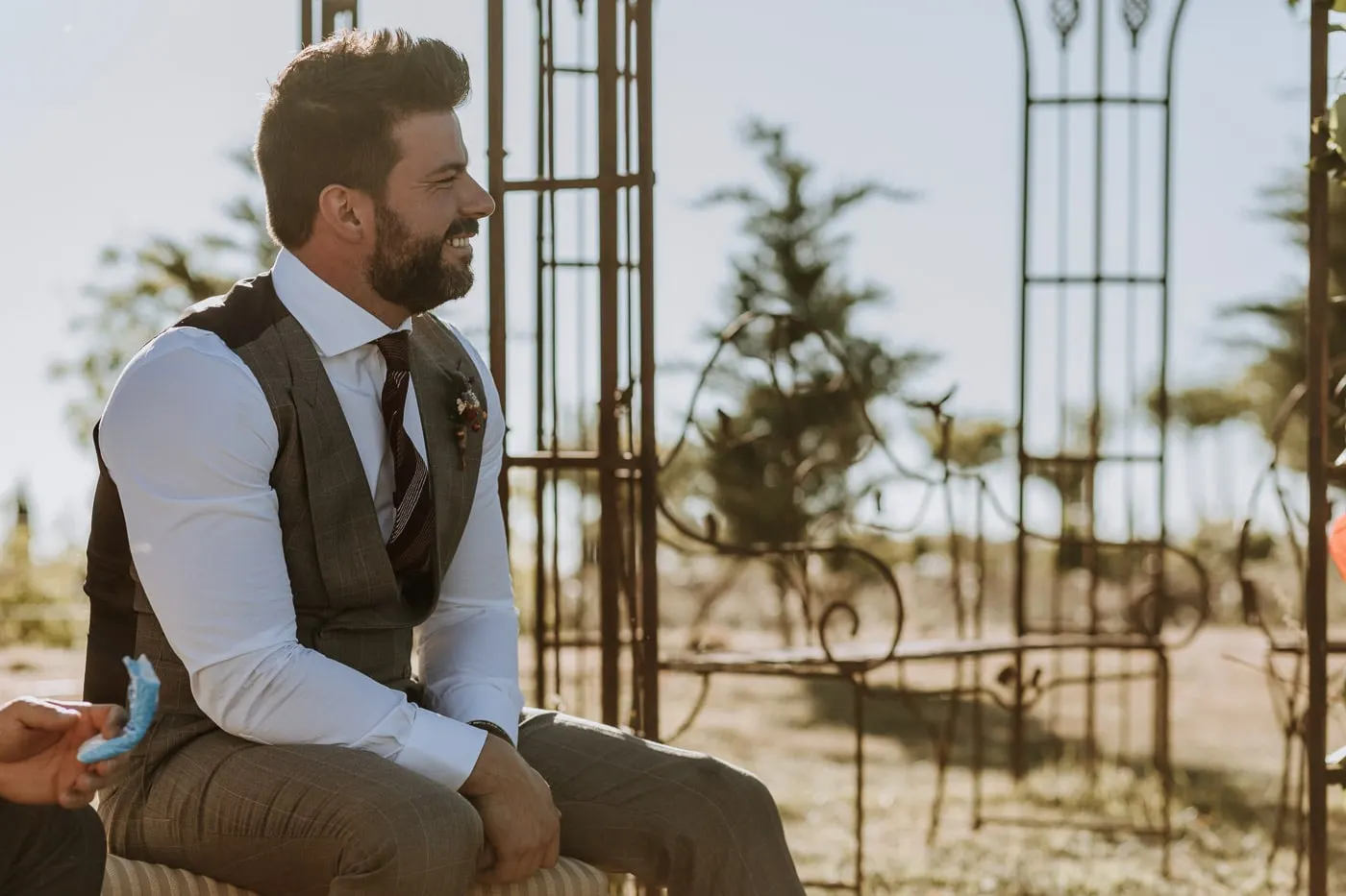 Groom seated by the iron arches of the gazebo, smiling, Salamanca