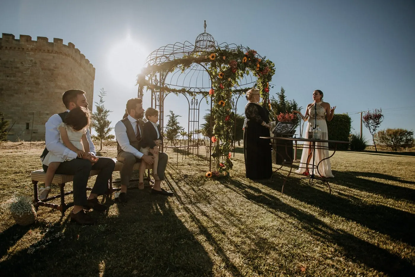 Ceremony under the flower-covered iron gazebo with the sun over the castle, Salamanca