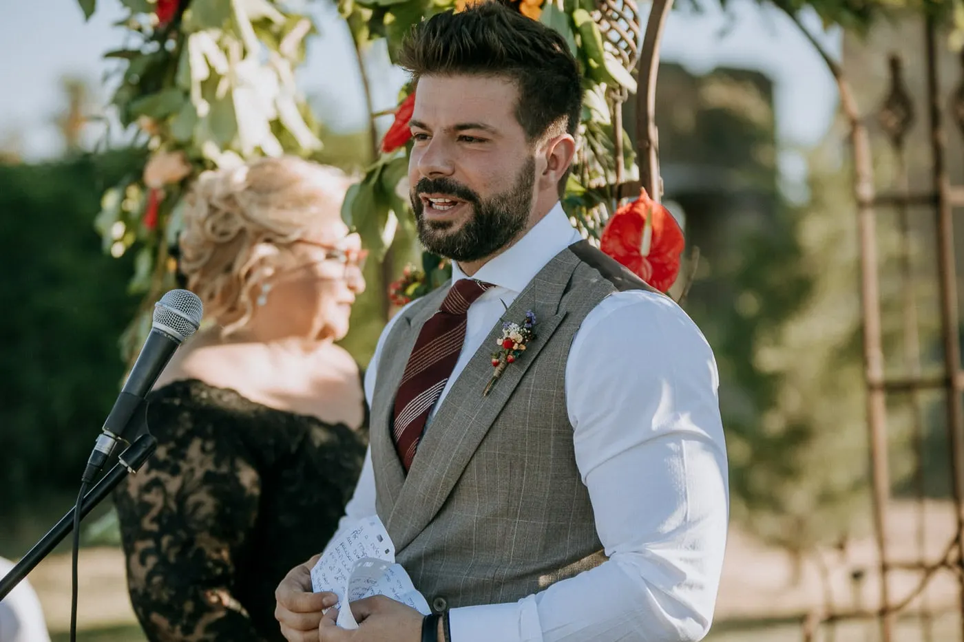 Groom smiling at the microphone under the flower arch, Salamanca