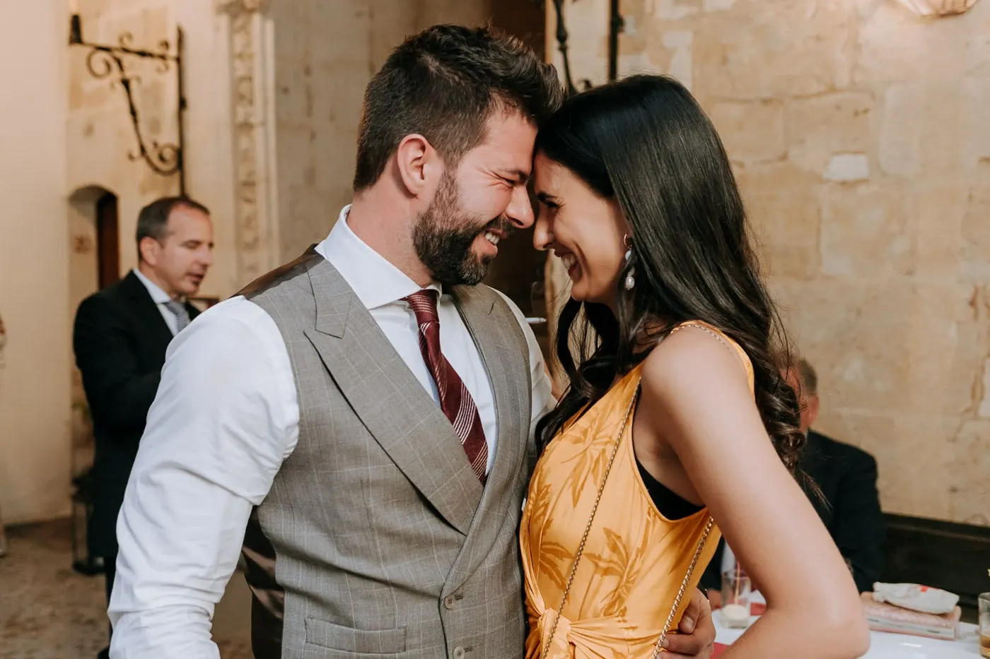 Groom and a friend in a yellow dress laughing forehead to forehead in the courtyard, Salamanca