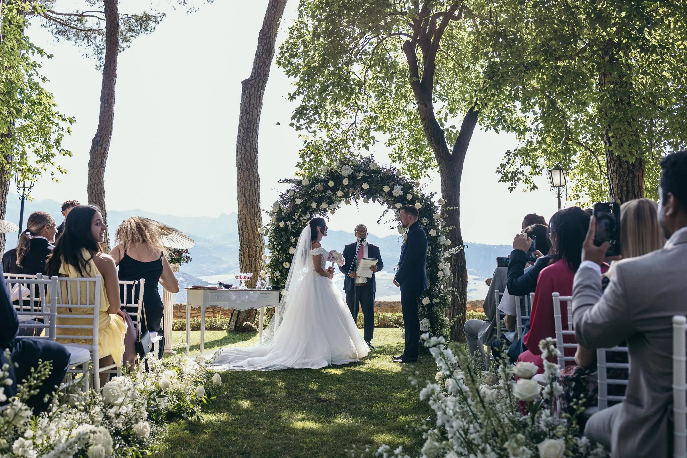 Sara reaches the flower arch at the end of the aisle, with the mountains of Ronda in the haze