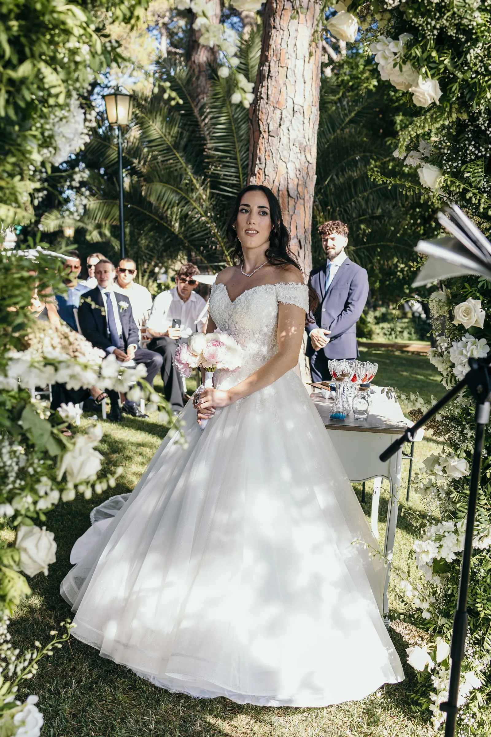 Sara, con su vestido de princesa, junto a la mesa de la ceremonia, entre verde y flores blancas