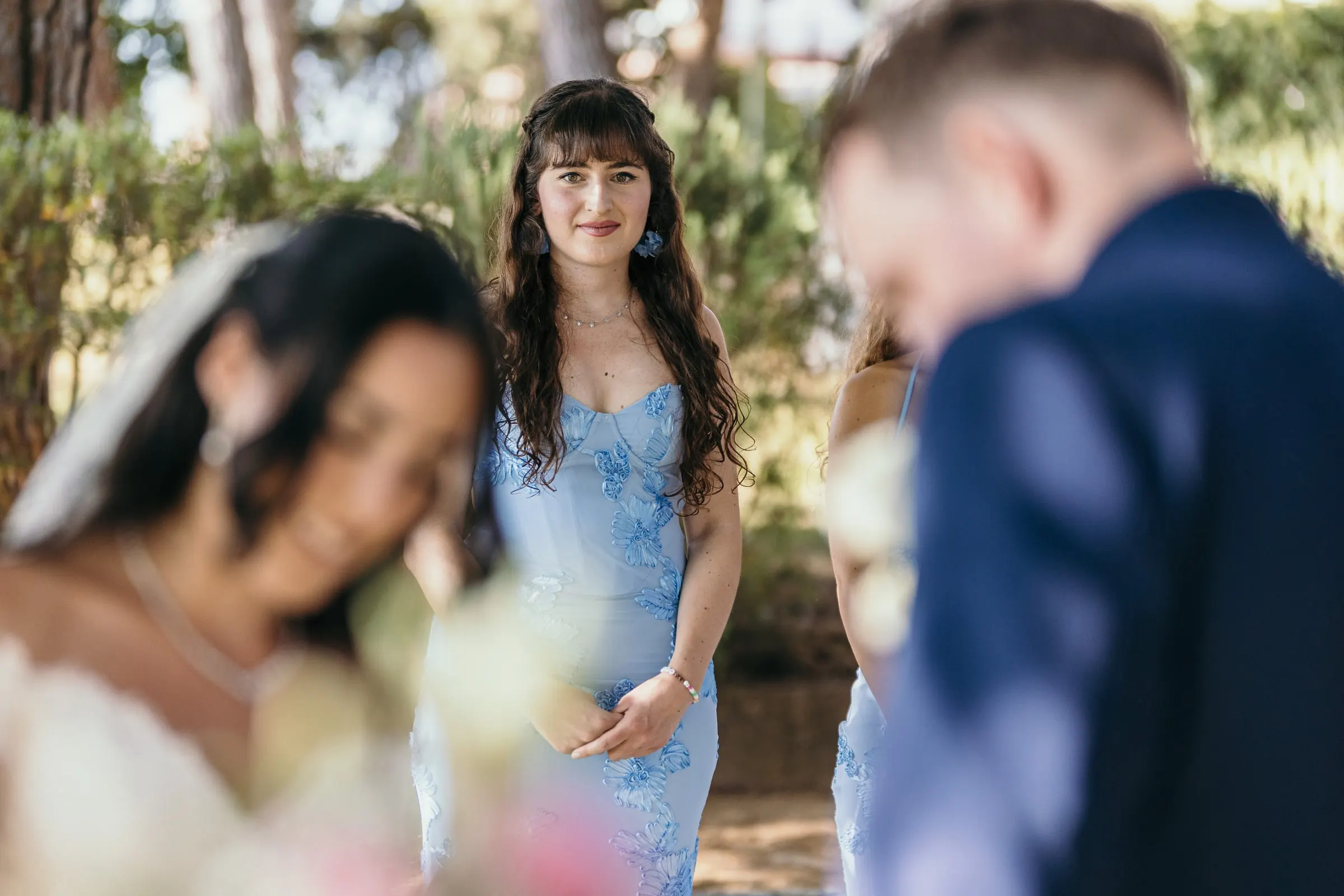 Una dama de honor de azul mira a los novios durante la ceremonia