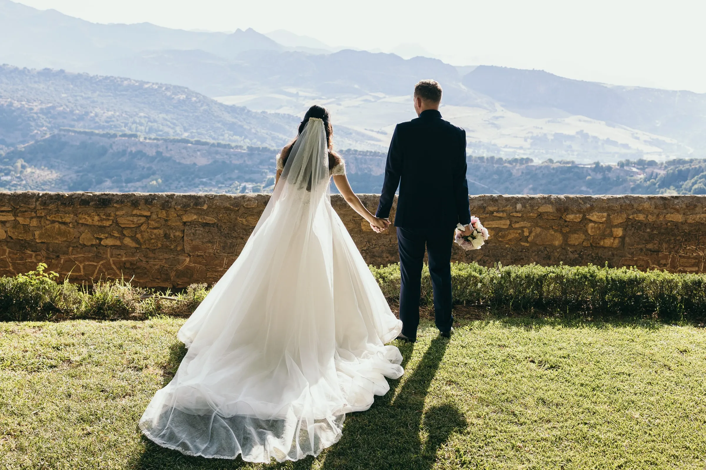 The couple from behind at the stone wall above the valley of Ronda