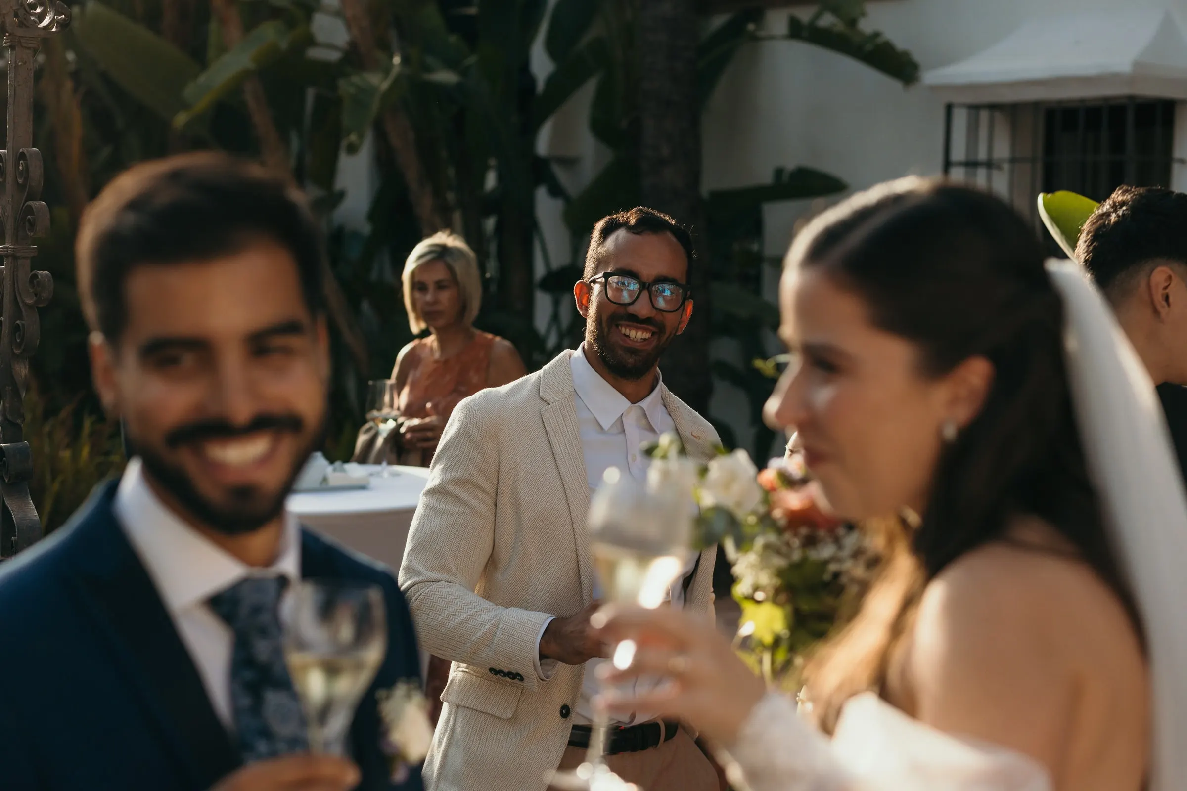El novio y los invitados brindan, con la novia y su velo en primer plano, Cortijo San Francisco, Estepona