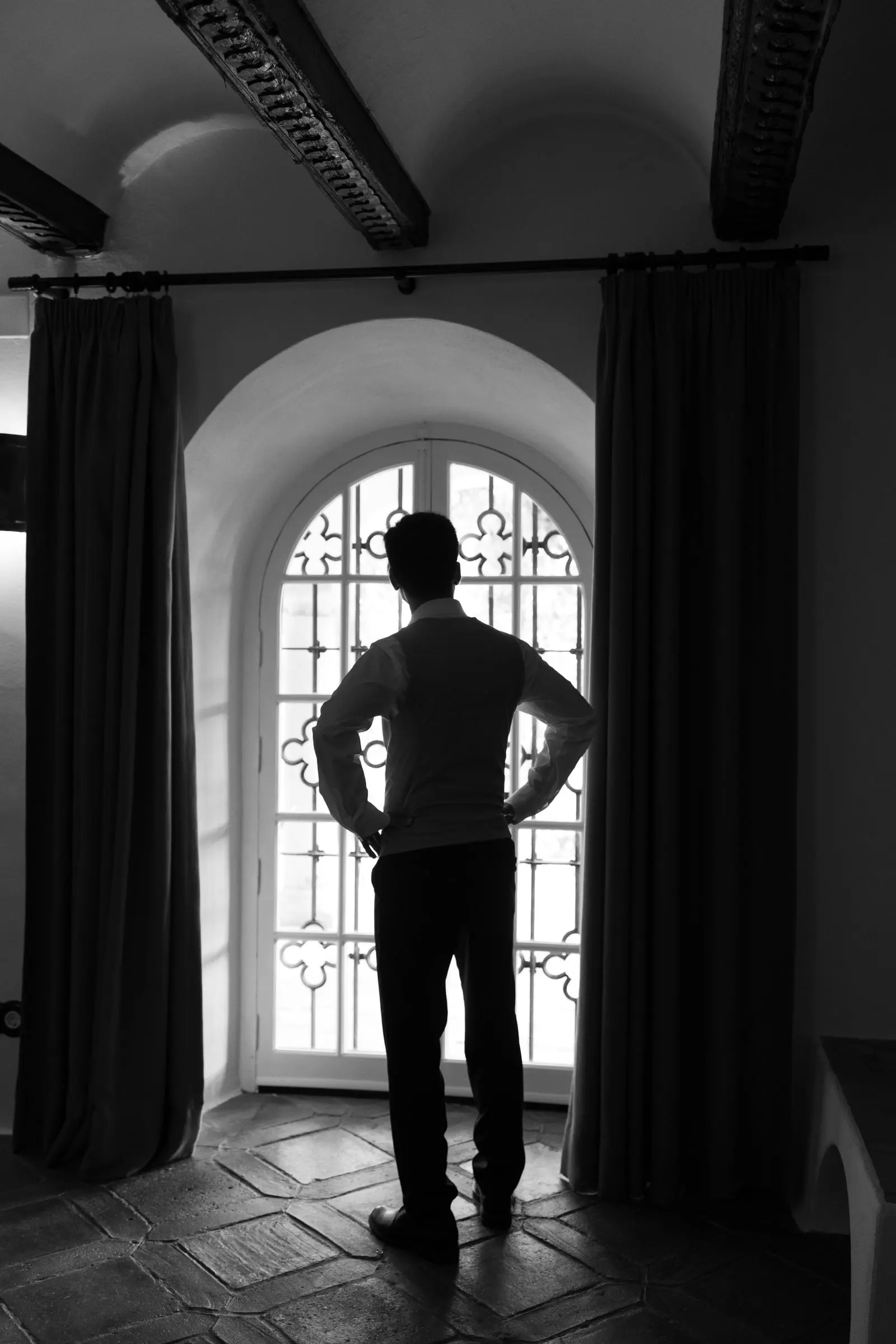 Black and white silhouette of the groom at an arched window, hands on hips, Cortijo San Francisco, Estepona