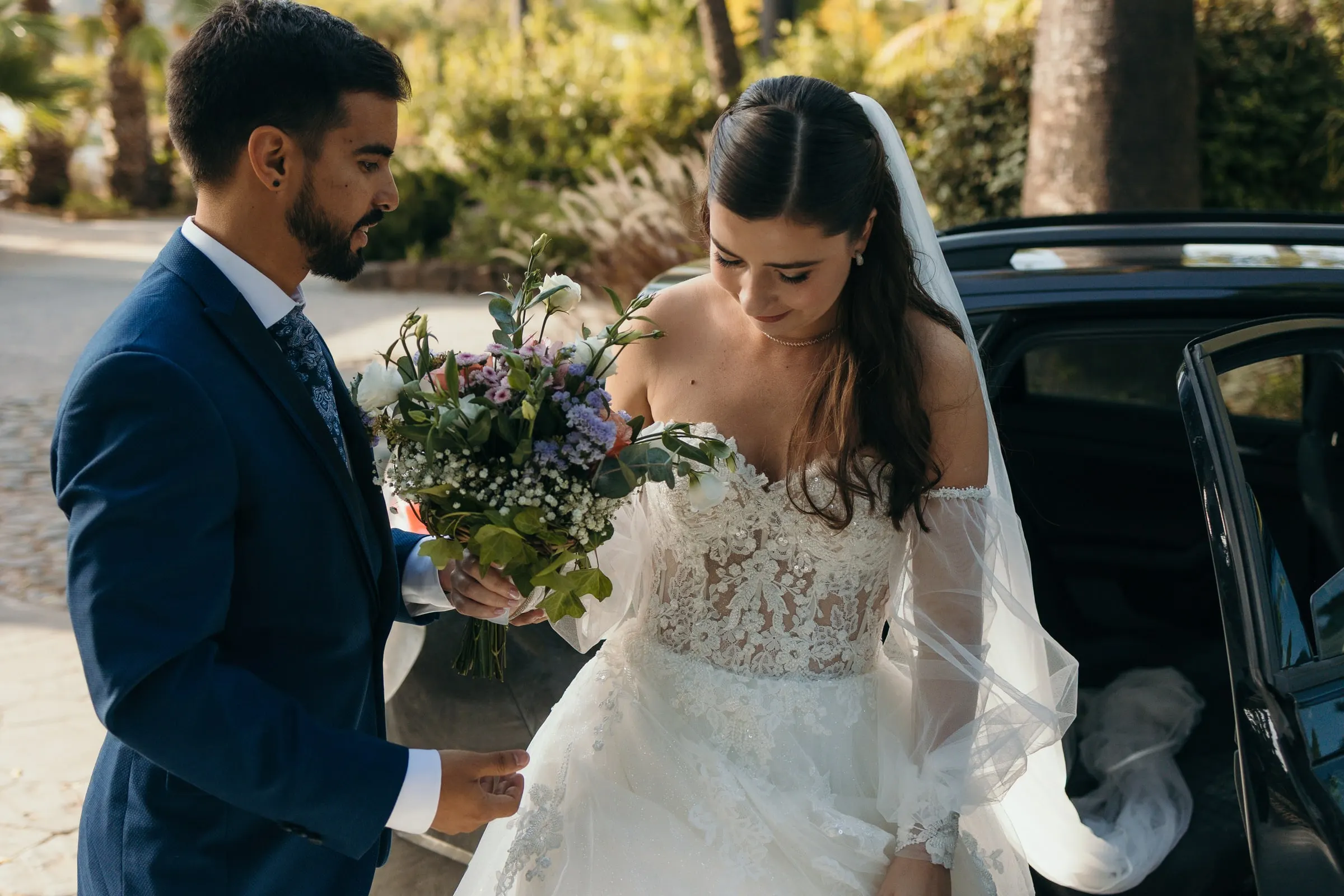 Groom helping the bride out of the car on arrival, bouquet in hand, Cortijo San Francisco, Estepona