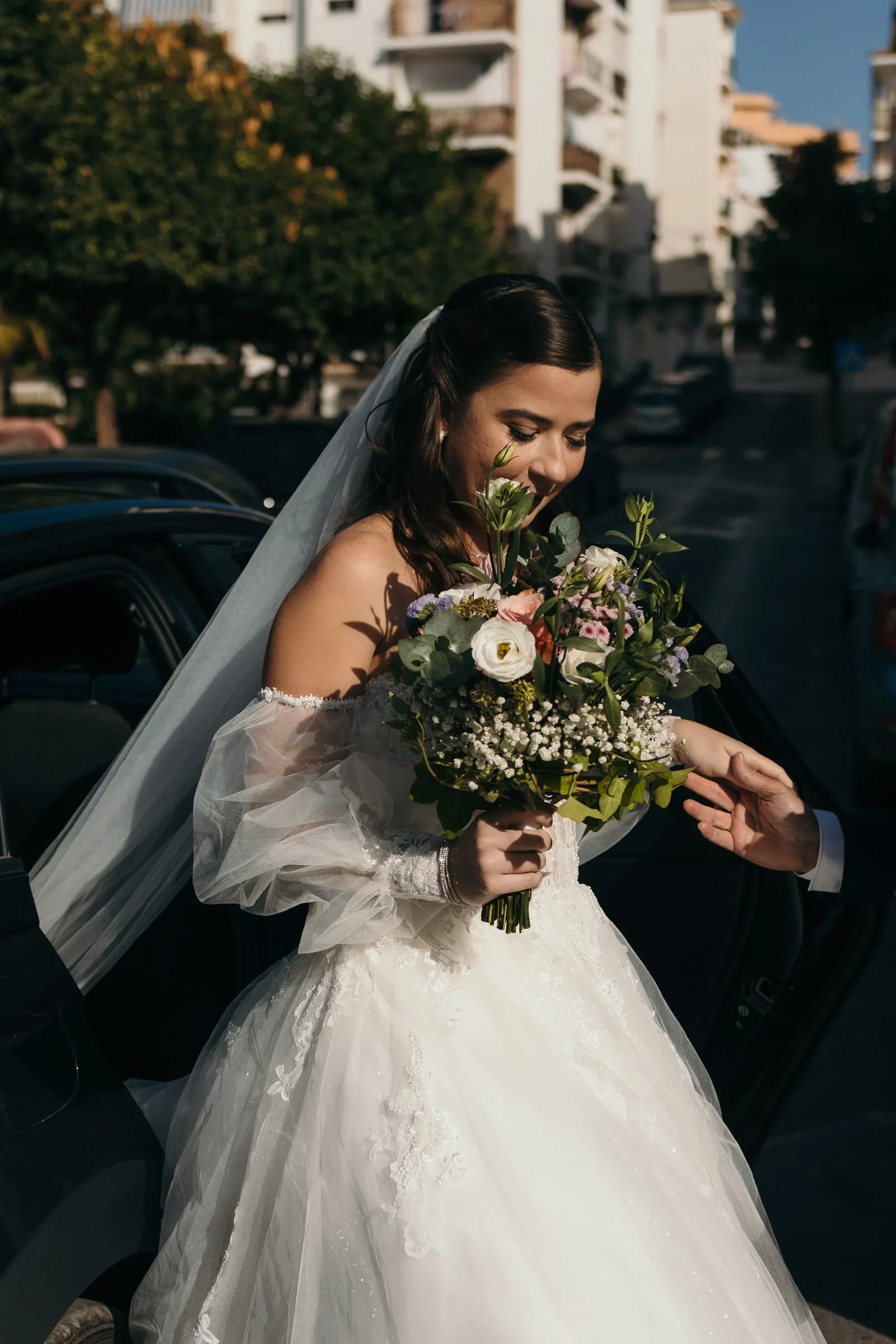 Bride arriving by car with her veil and bouquet in late afternoon sun, Cortijo San Francisco, Estepona