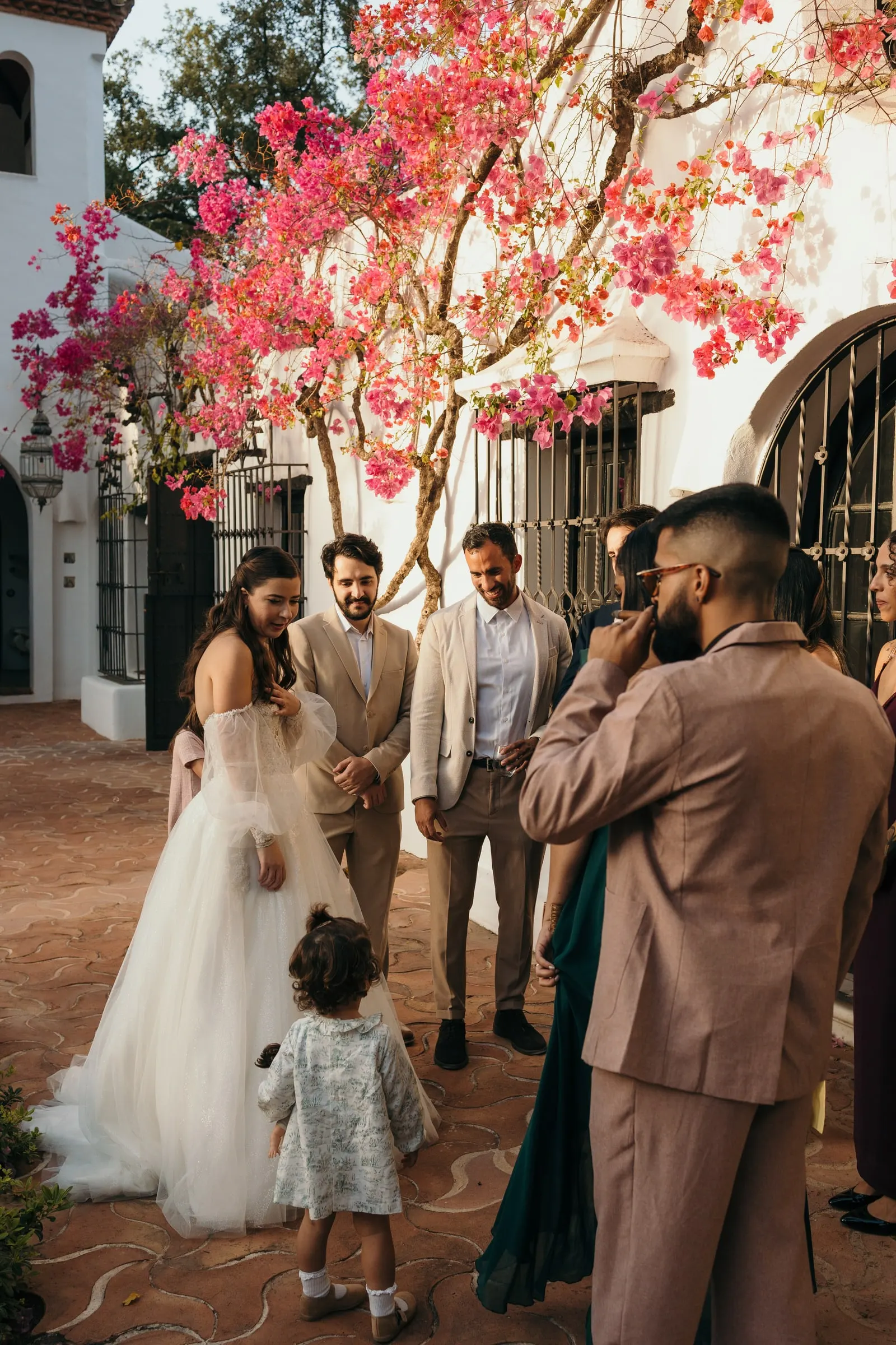 Bride greeting guests and a little girl under a bougainvillea in bloom, Cortijo San Francisco, Estepona