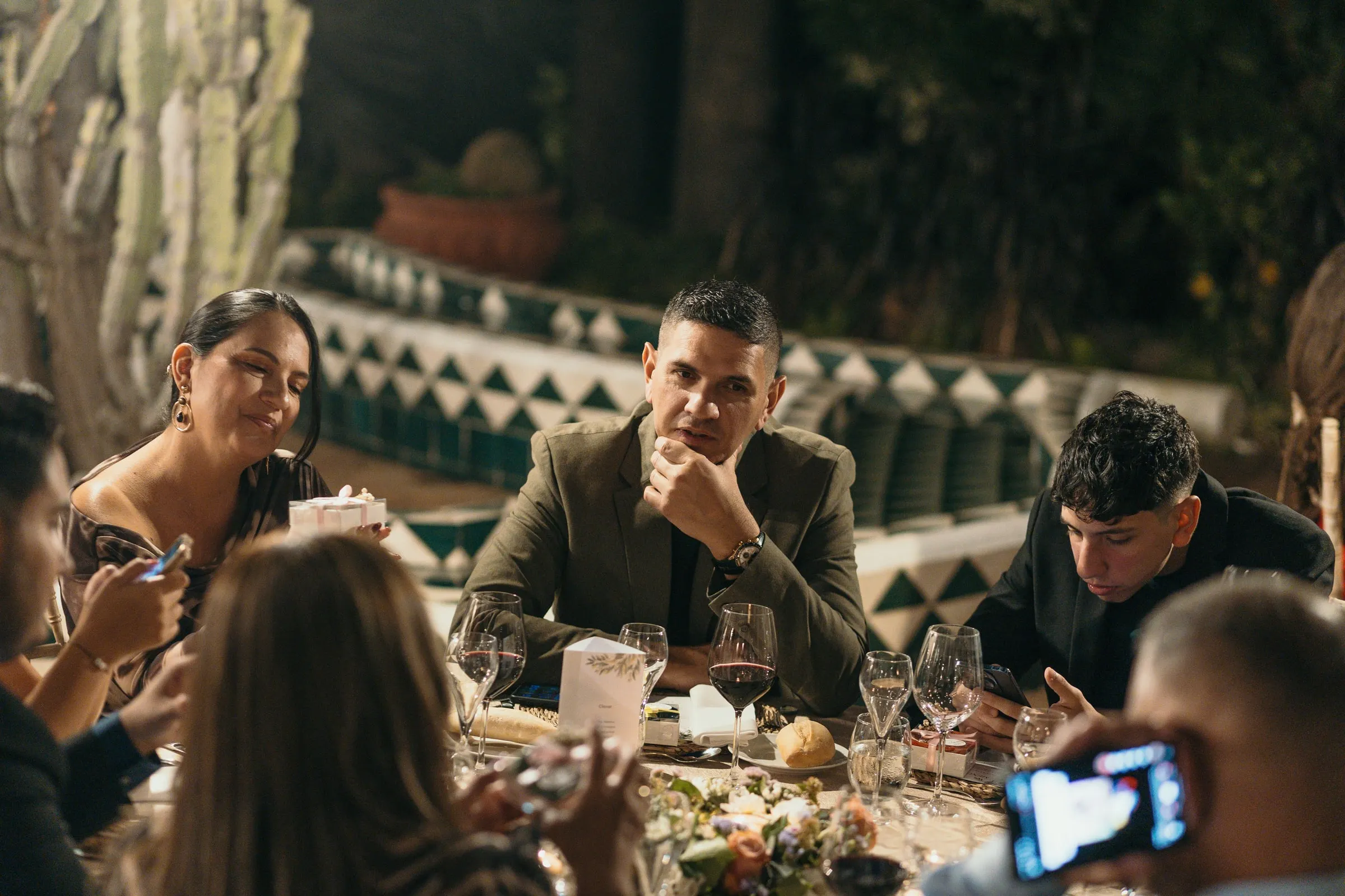 Invitados charlando en la cena mientras uno graba con el móvil, Cortijo San Francisco, Estepona