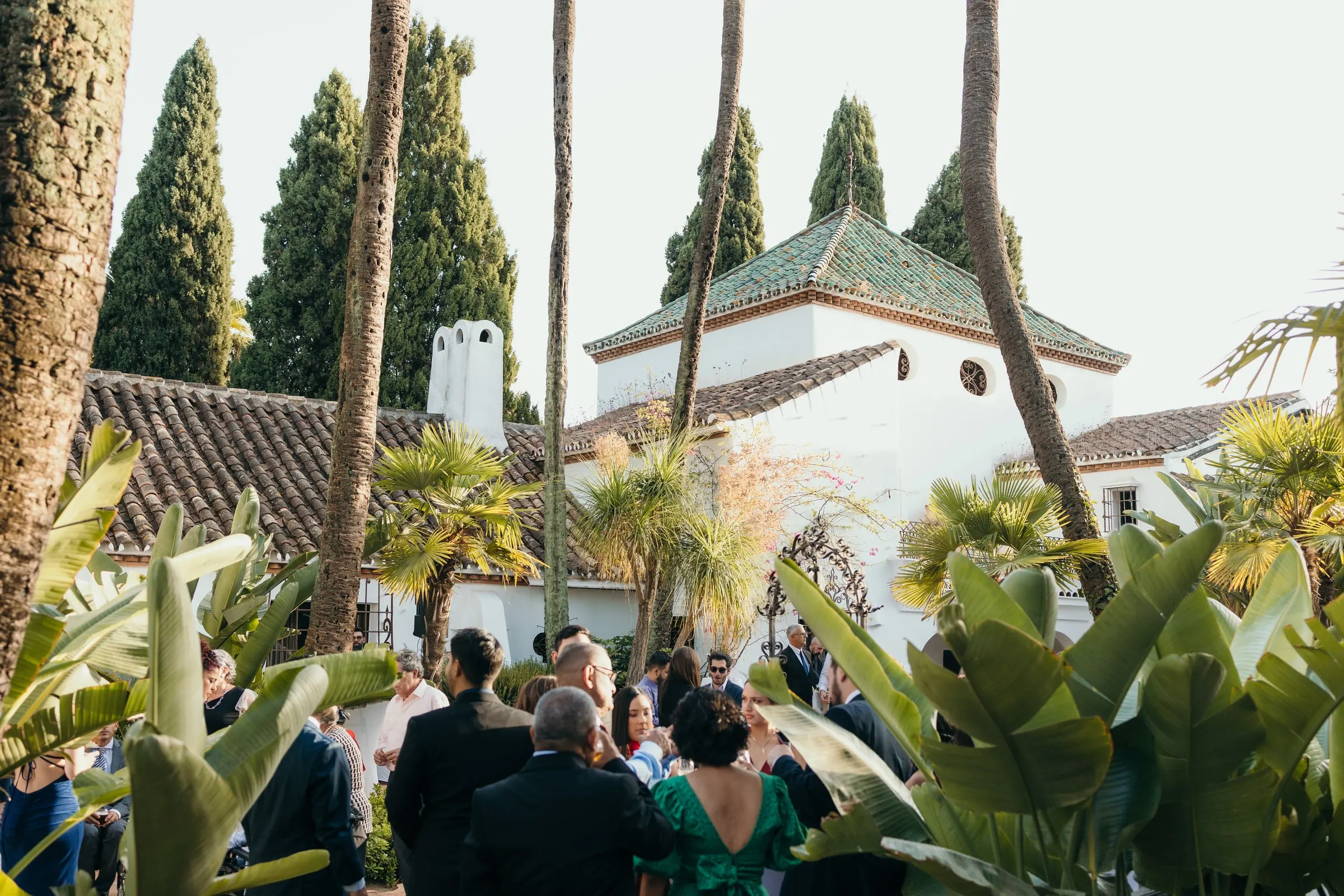 Los invitados reunidos en un jardín tropical frente a la capilla blanca, Cortijo San Francisco, Estepona