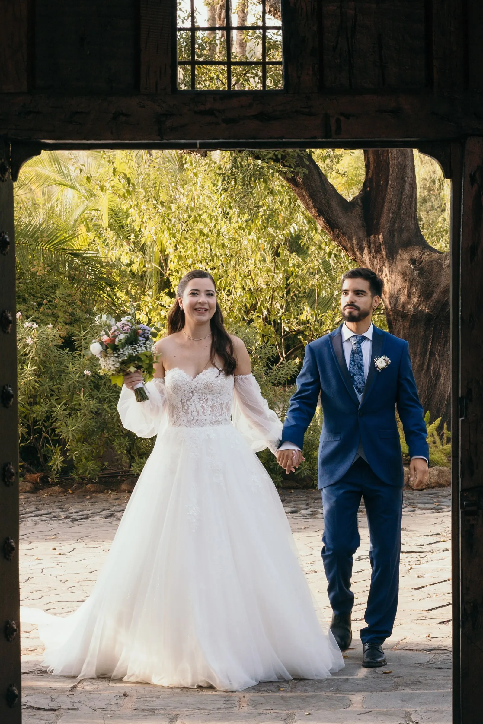 Los novios entran de la mano por un portón de madera, Cortijo San Francisco, Estepona