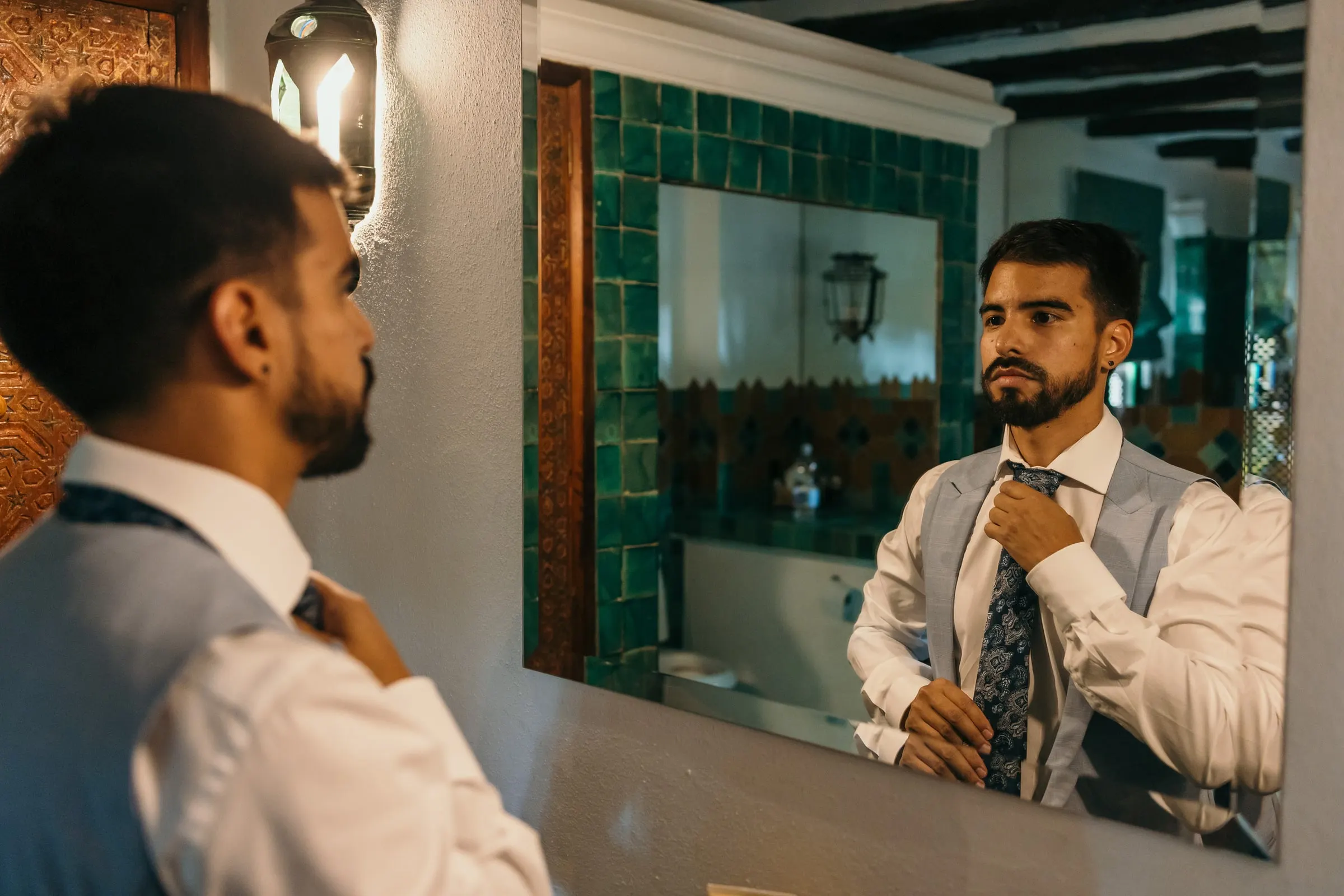 El novio se anuda la corbata frente al espejo de un baño con azulejos, Cortijo San Francisco, Estepona