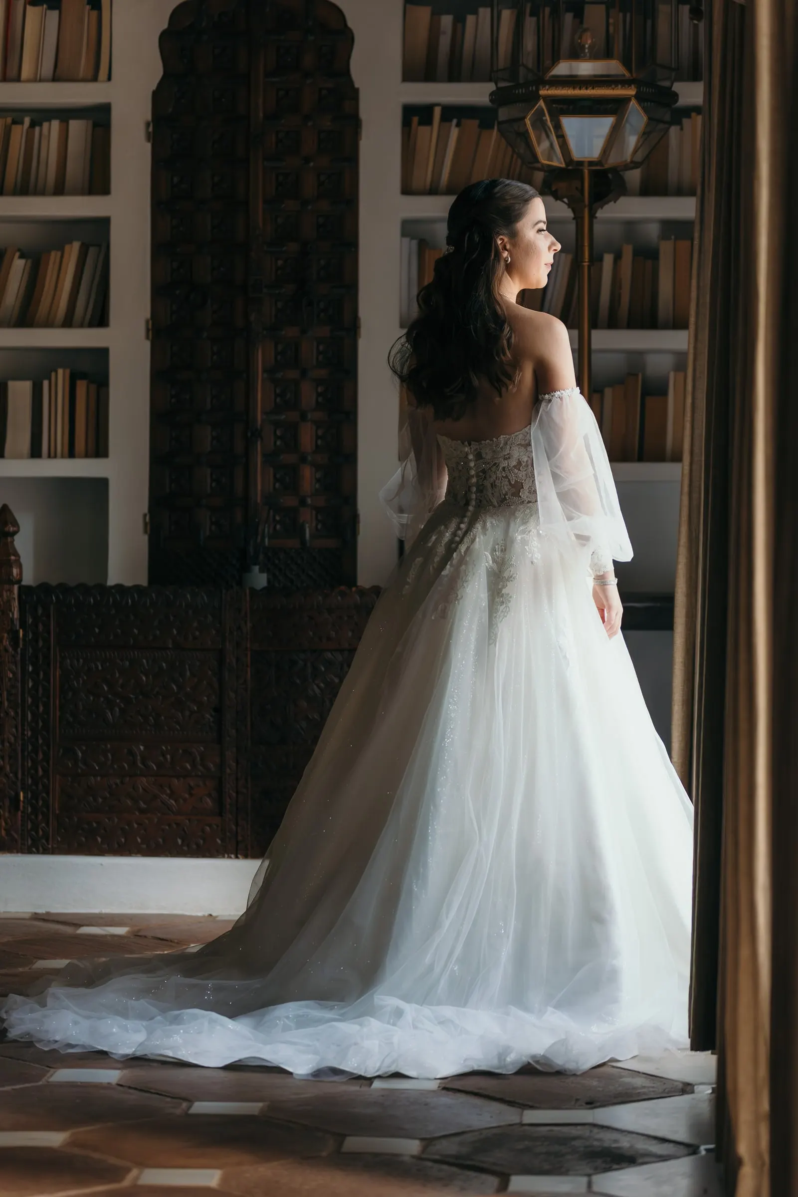 La novia de espaldas en la biblioteca, con la larga cola sobre el suelo de barro, Cortijo San Francisco, Estepona