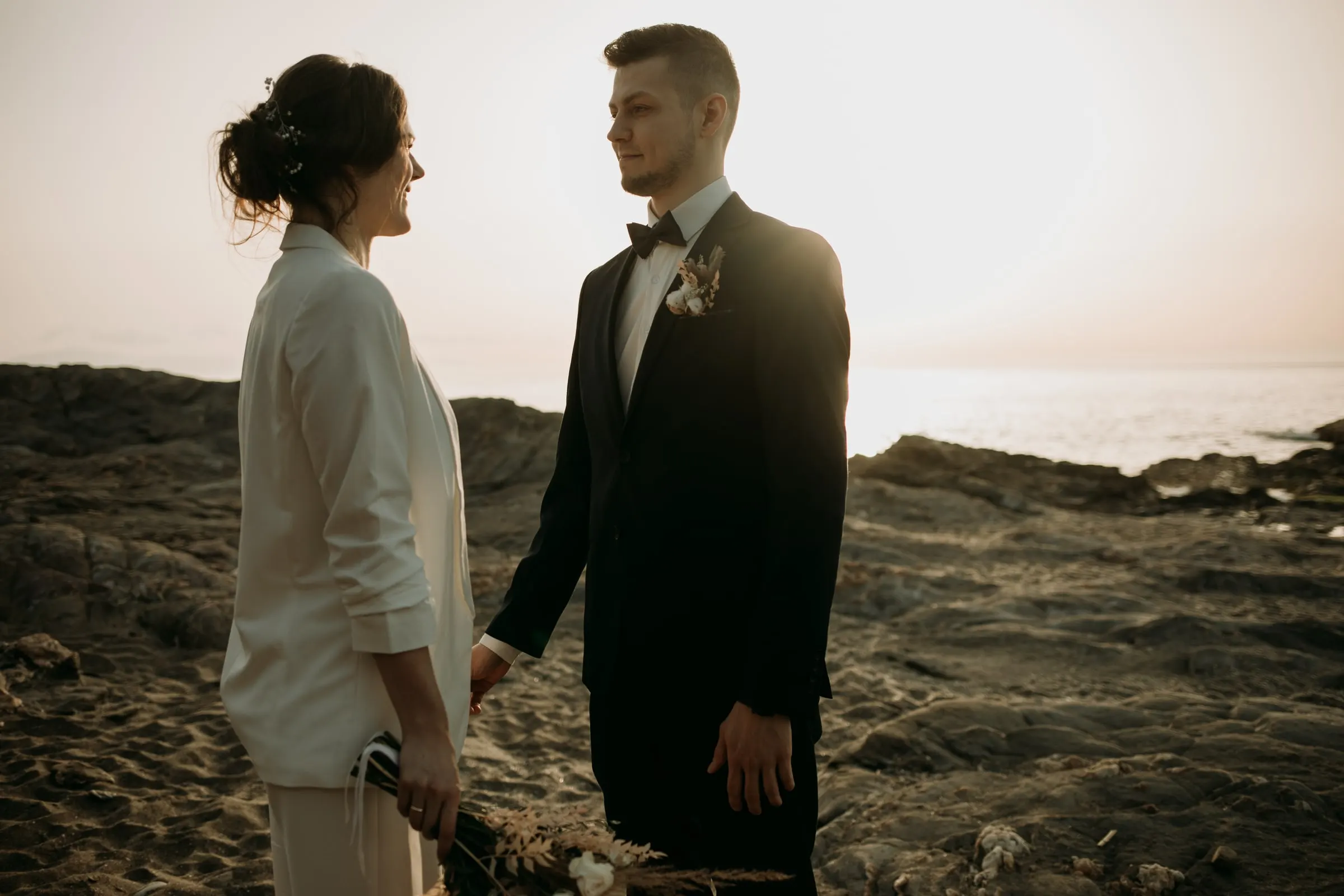 Los novios frente a frente en una costa de rocas al atardecer, postboda en la Costa del Sol