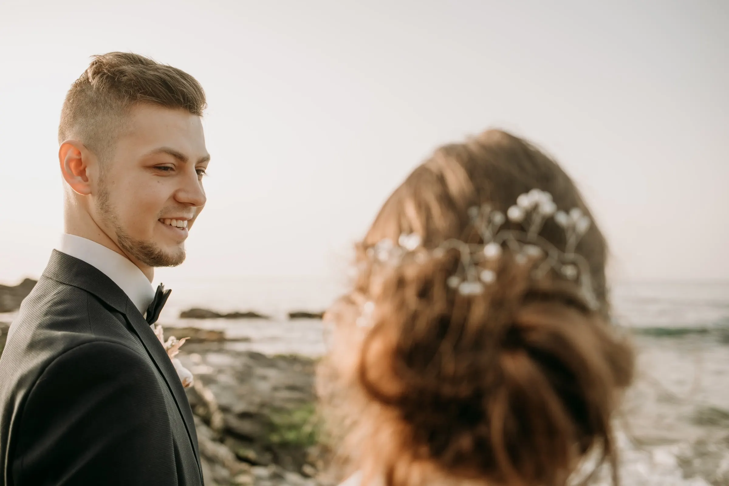 El novio sonríe a la novia, que lleva ramitas de paniculata en el pelo