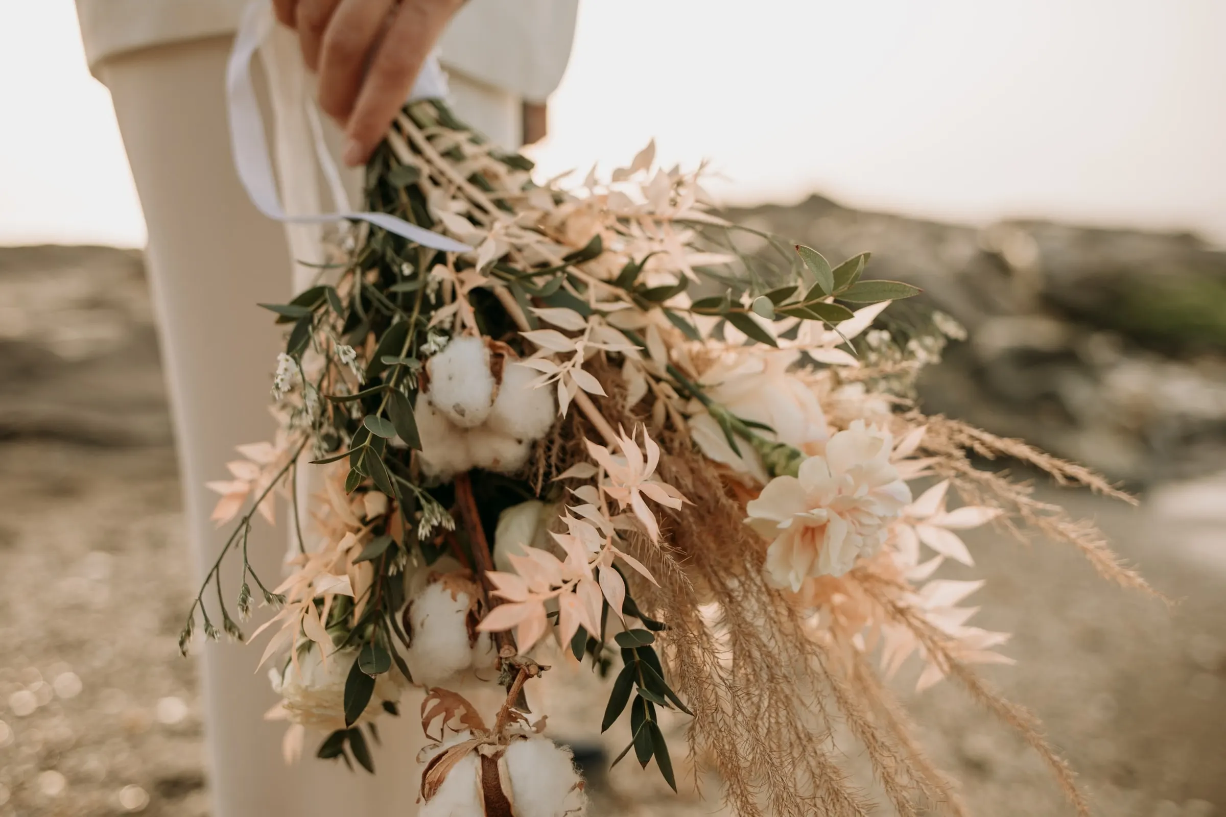 Ramo de pampas, flores de algodón y hojas secas junto al pantalón blanco de la novia