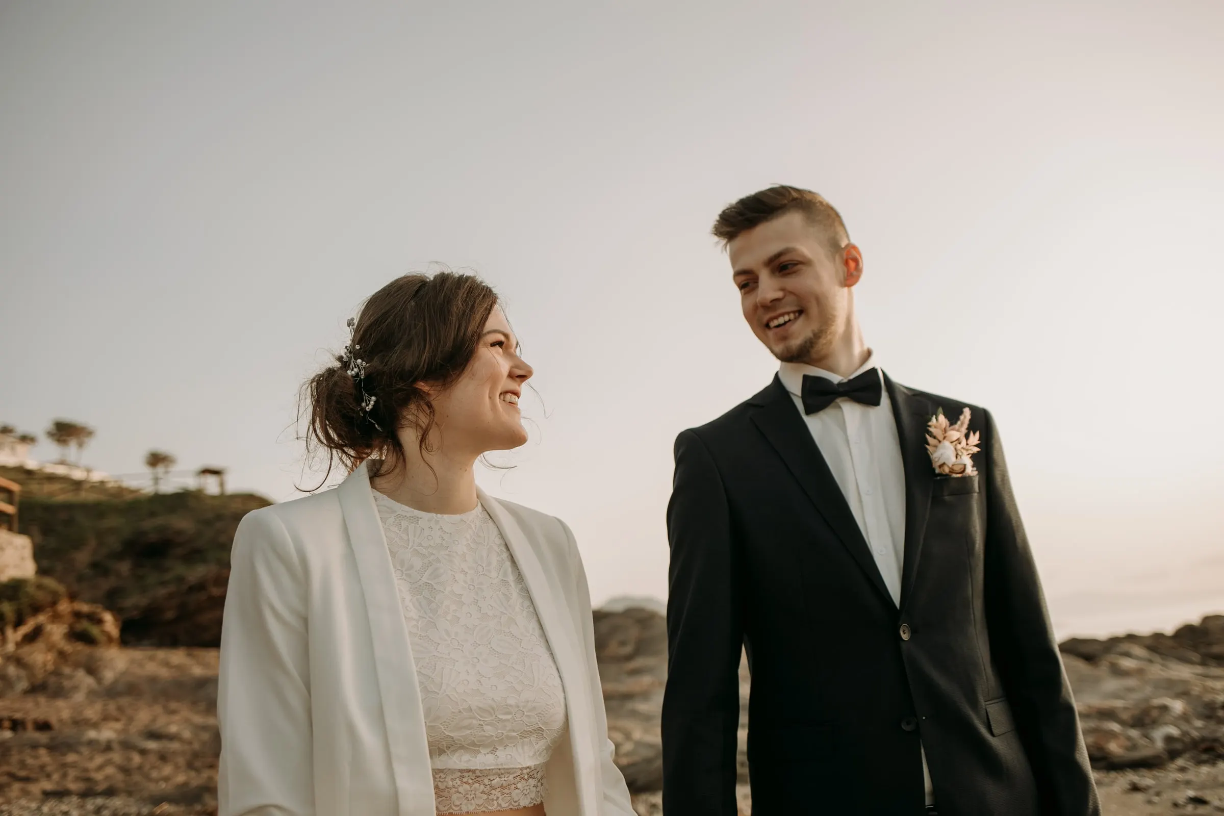Los novios ríen juntos en la orilla en la hora dorada