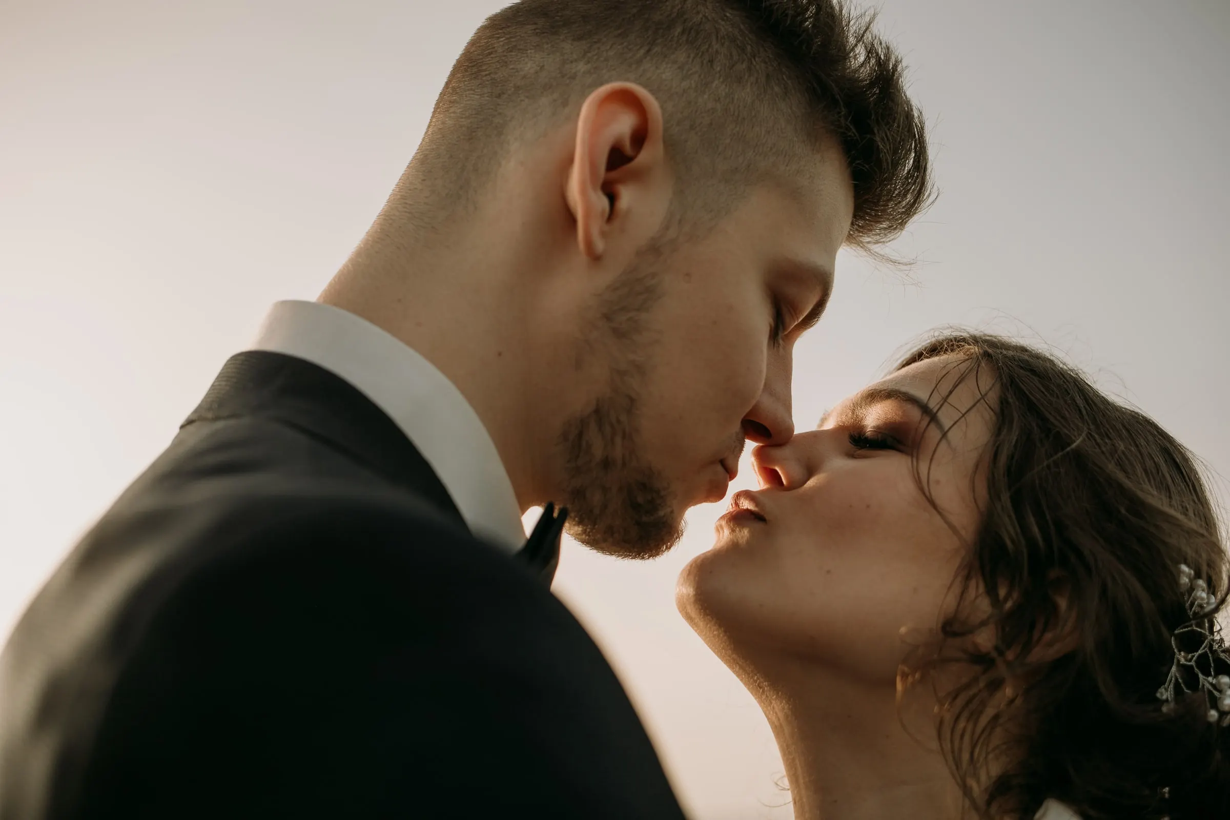 Primer plano del beso de los novios ante el cielo suave del atardecer