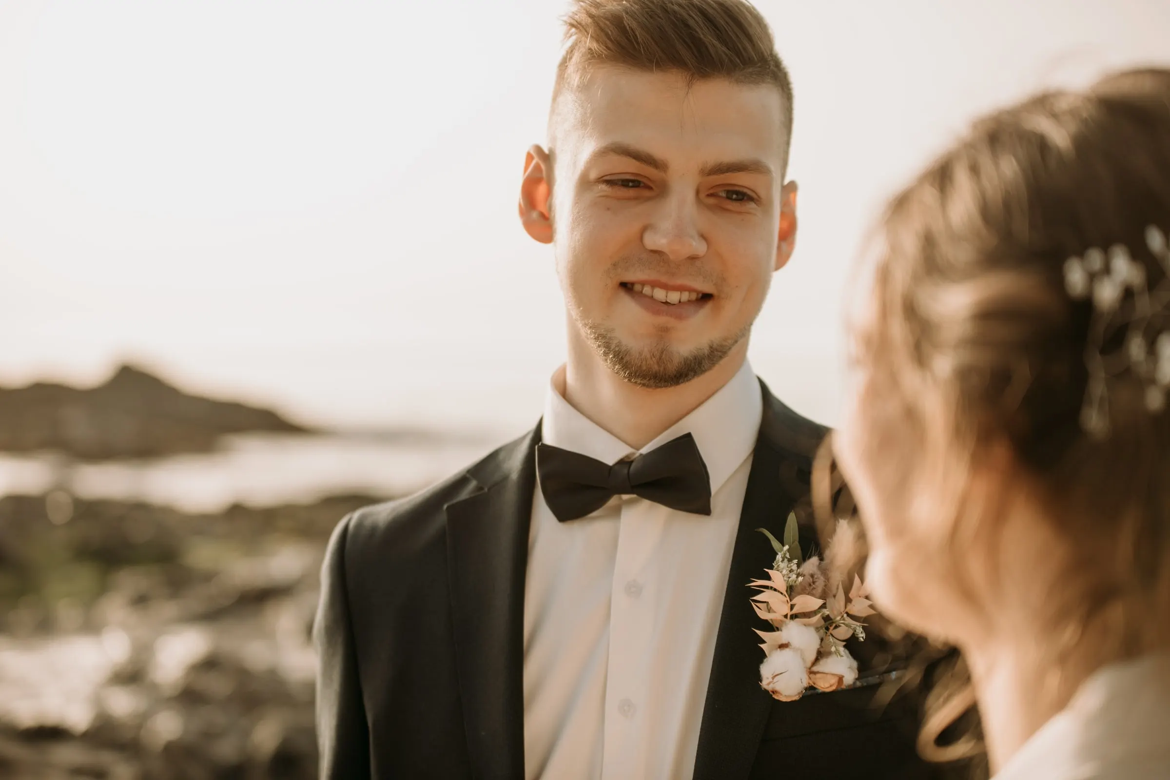 El novio ríe con la novia, con un prendido de flores secas en la solapa