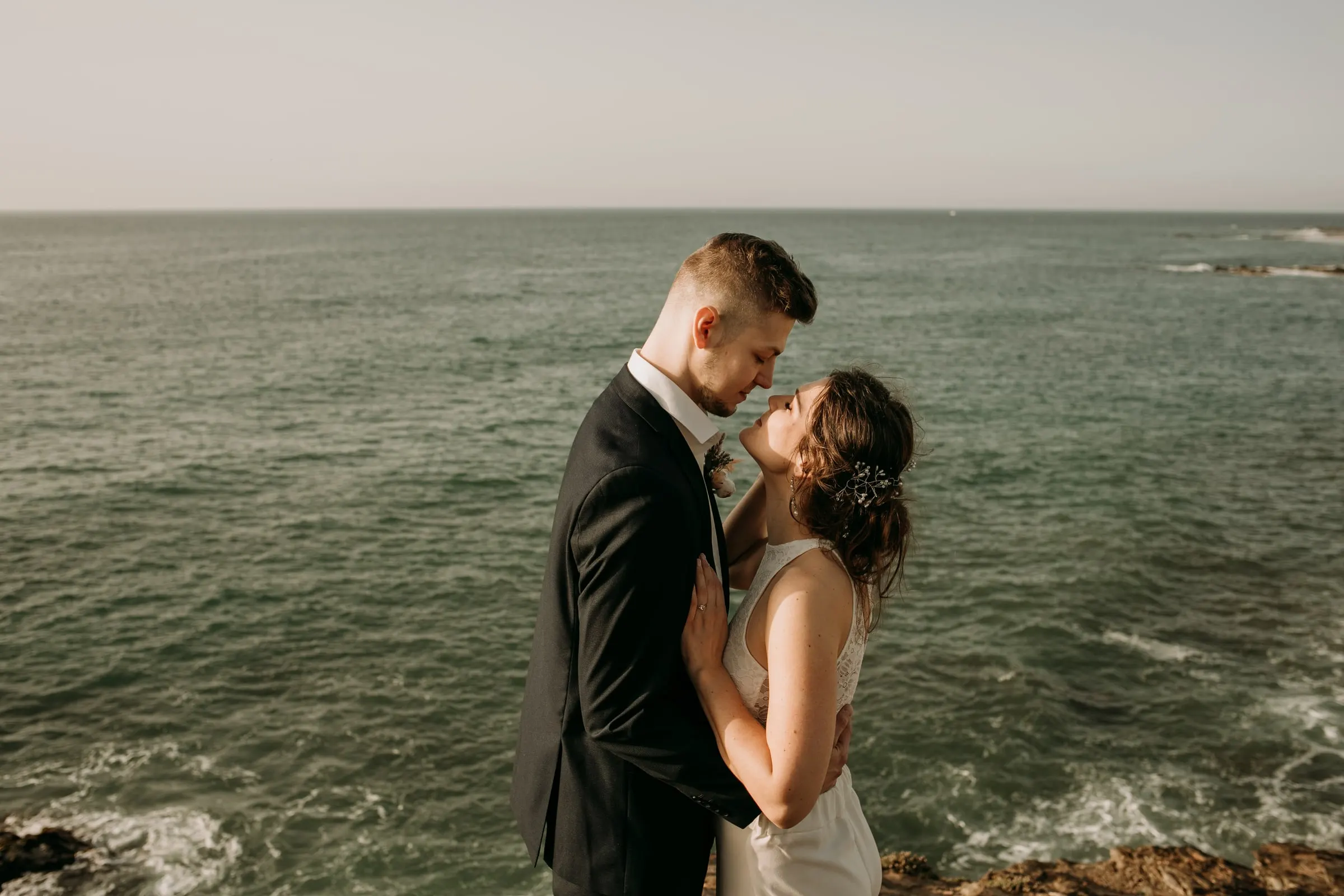 Beso de los novios en lo alto de un acantilado sobre el mar verde, postboda en la Costa del Sol
