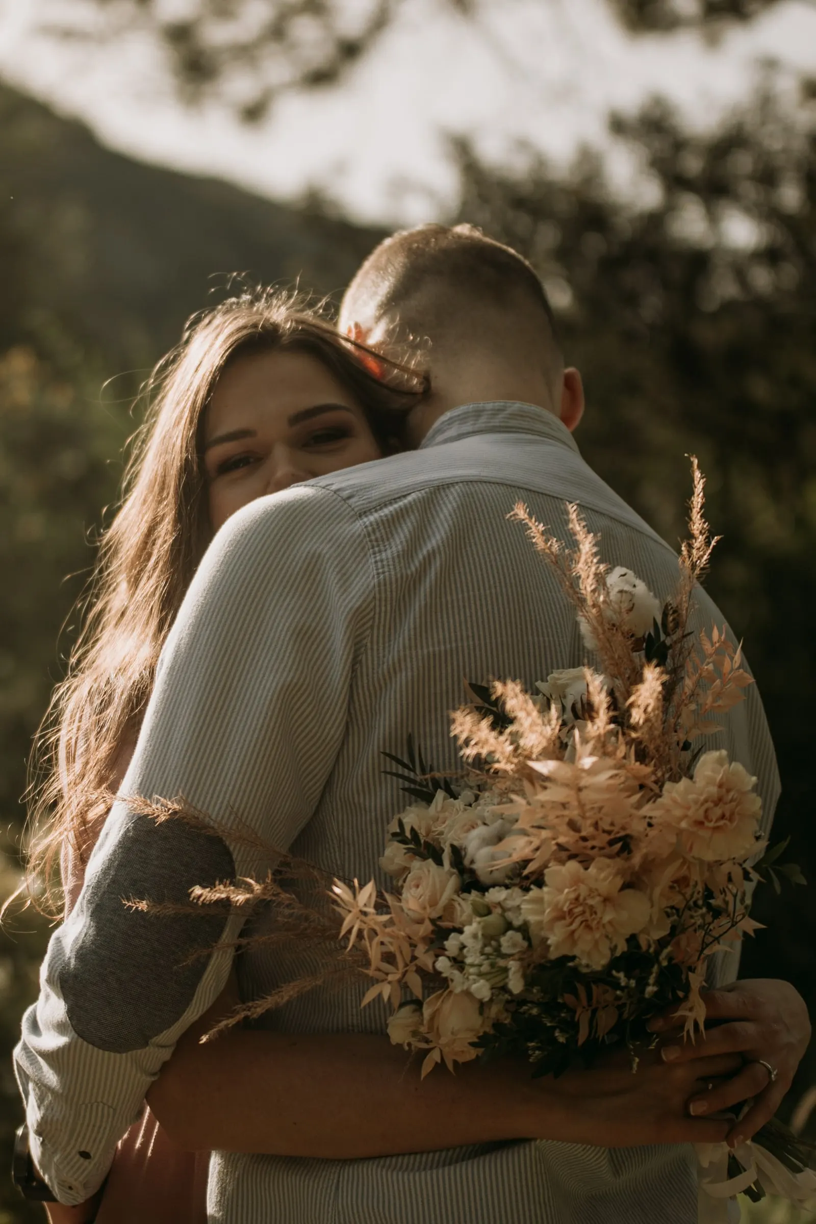 Bride-to-be hugging her fiancé and smiling over his shoulder