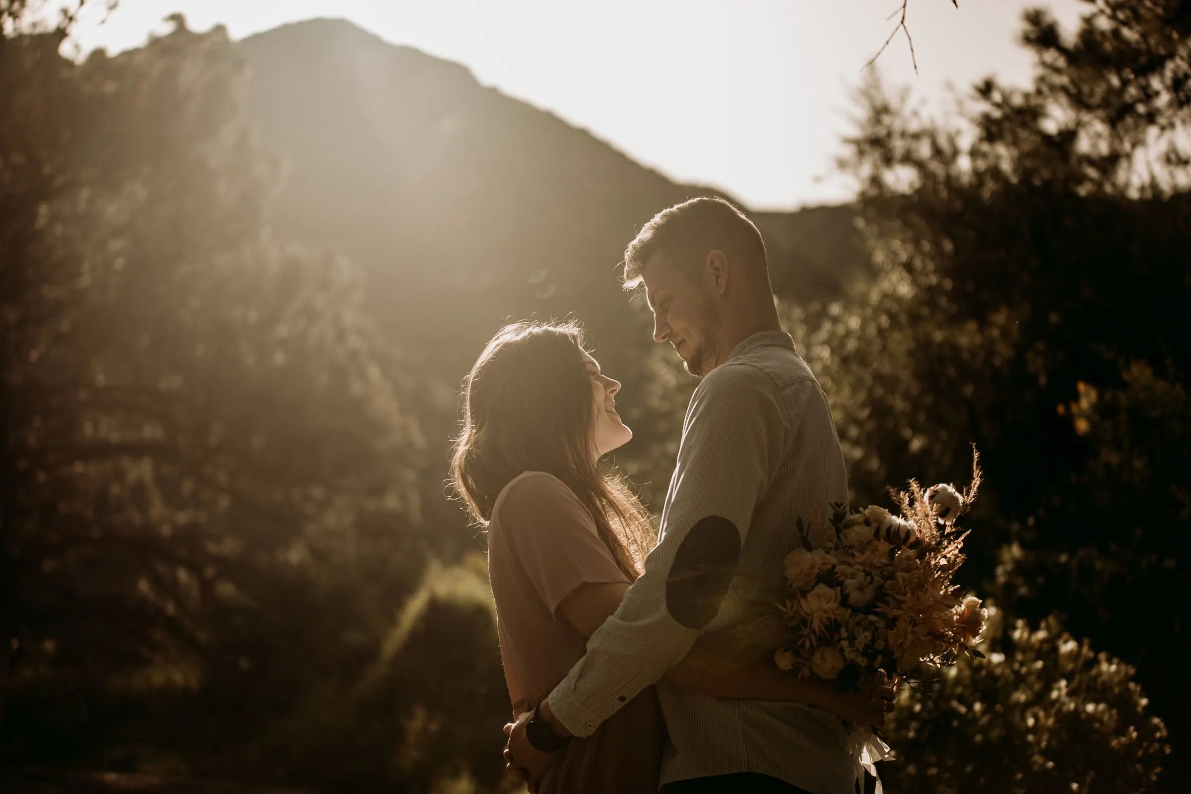 Couple looking at each other, the sun over the mountain ridge behind them